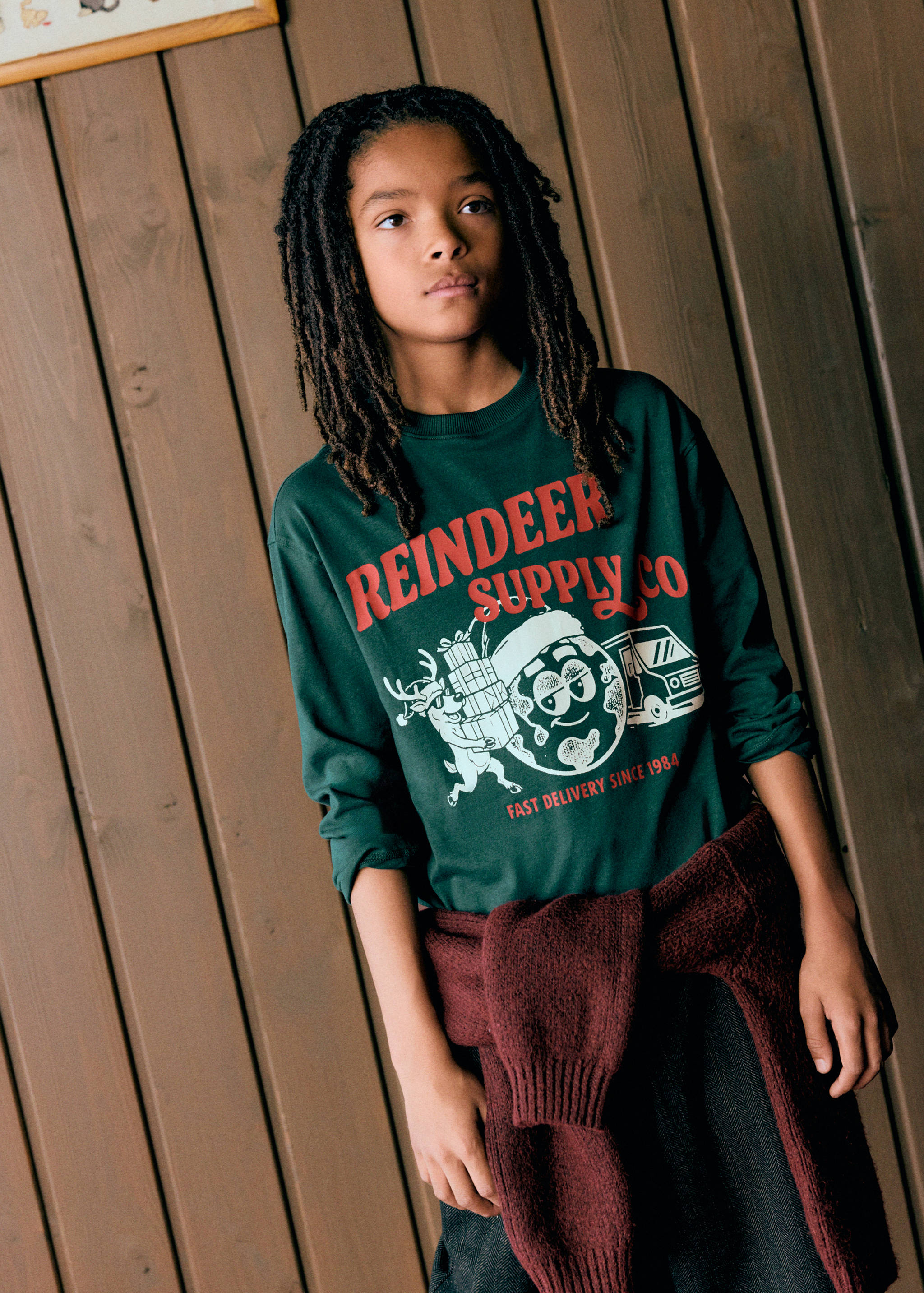 Dark green long-sleeved t-shirt with a festive Reindeer Supply Co graphic print.