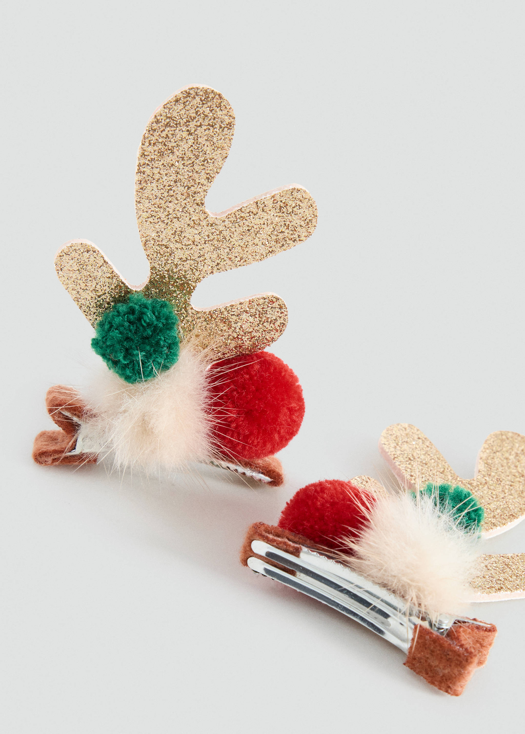 Two reindeer hair clips featuring gold glitter antlers, red and green pom-poms, and cream faux-fur.