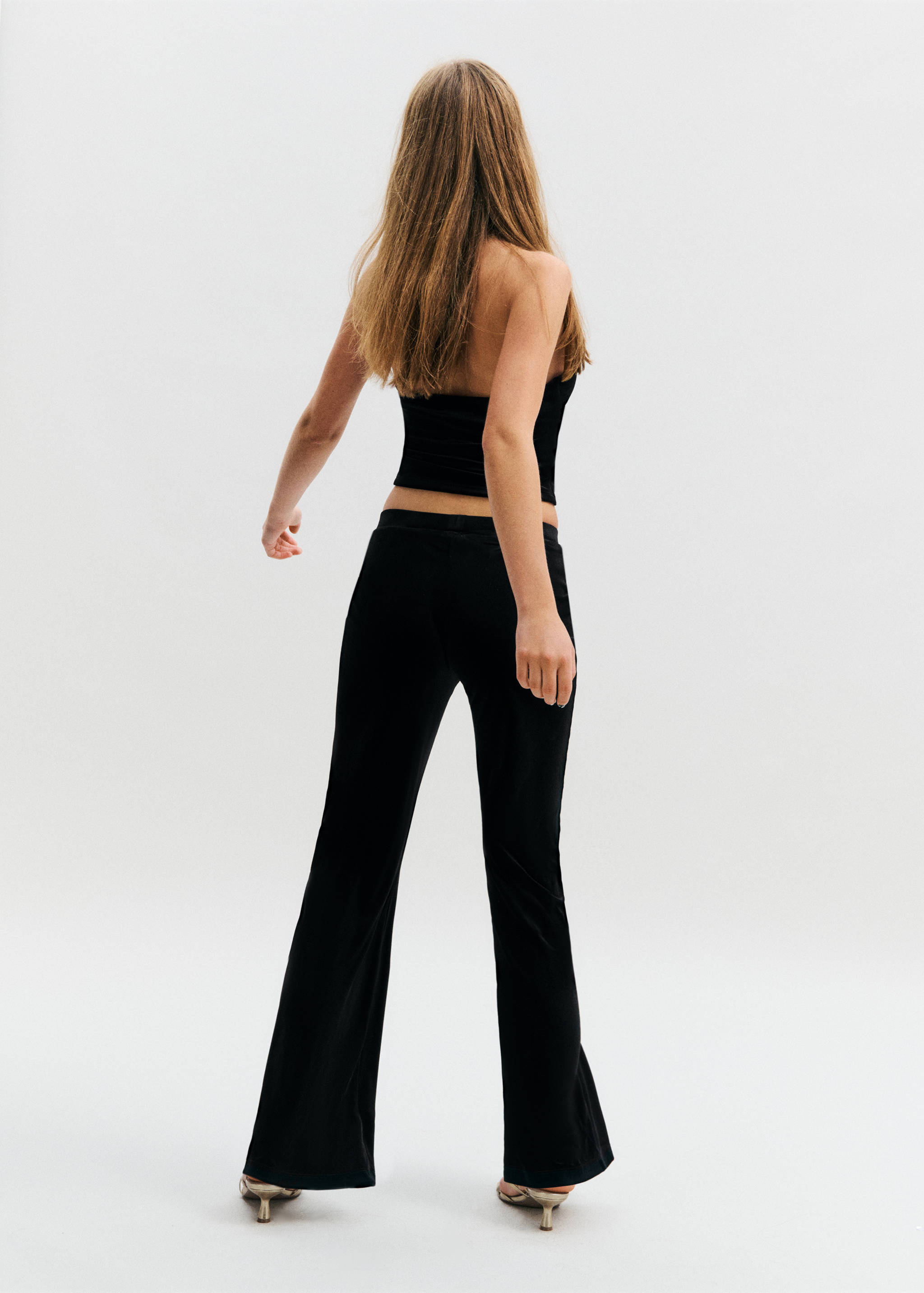 Black low-rise flared trousers, back view.