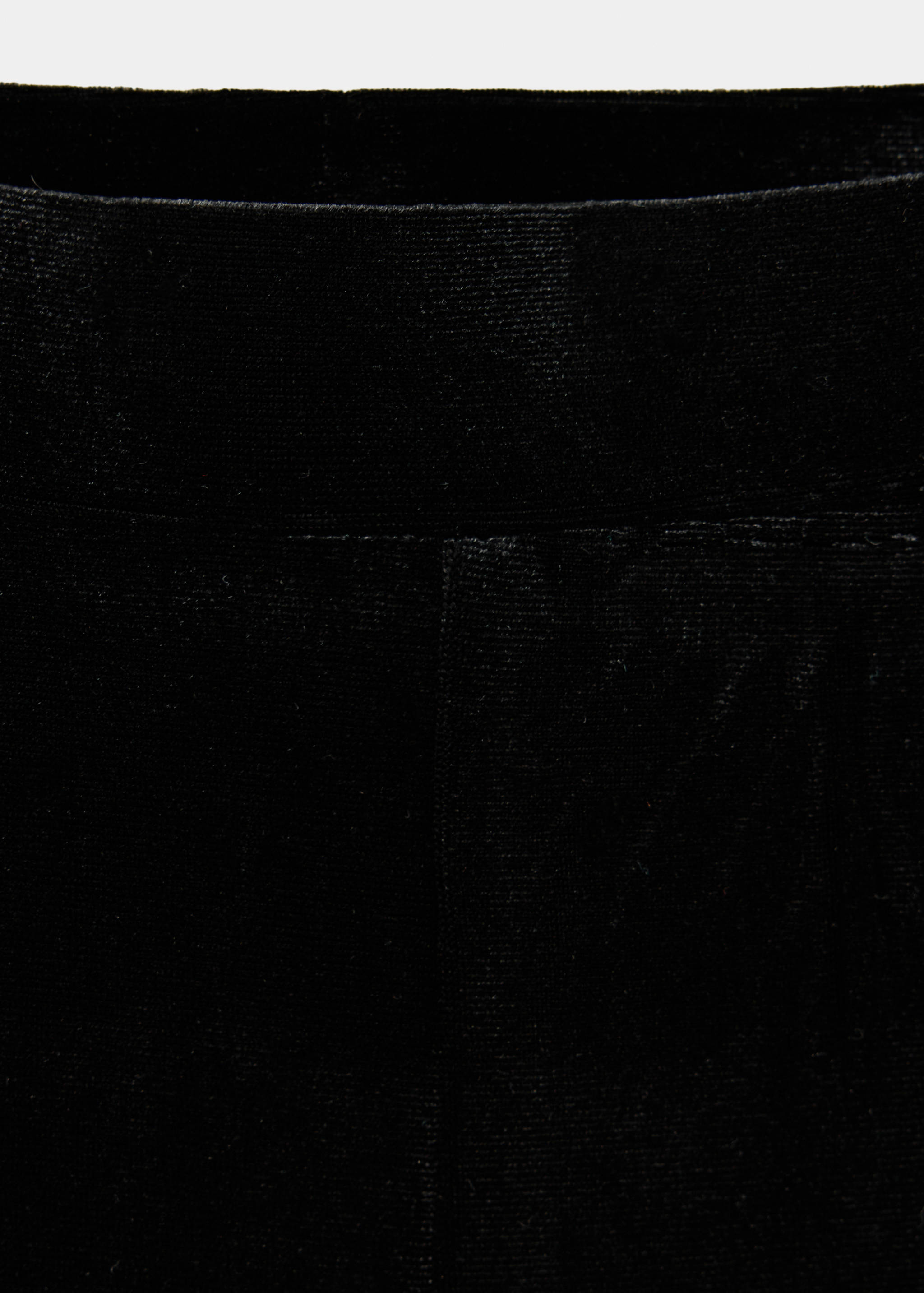 Close-up of black trousers featuring a smooth, textured elastic waistband.