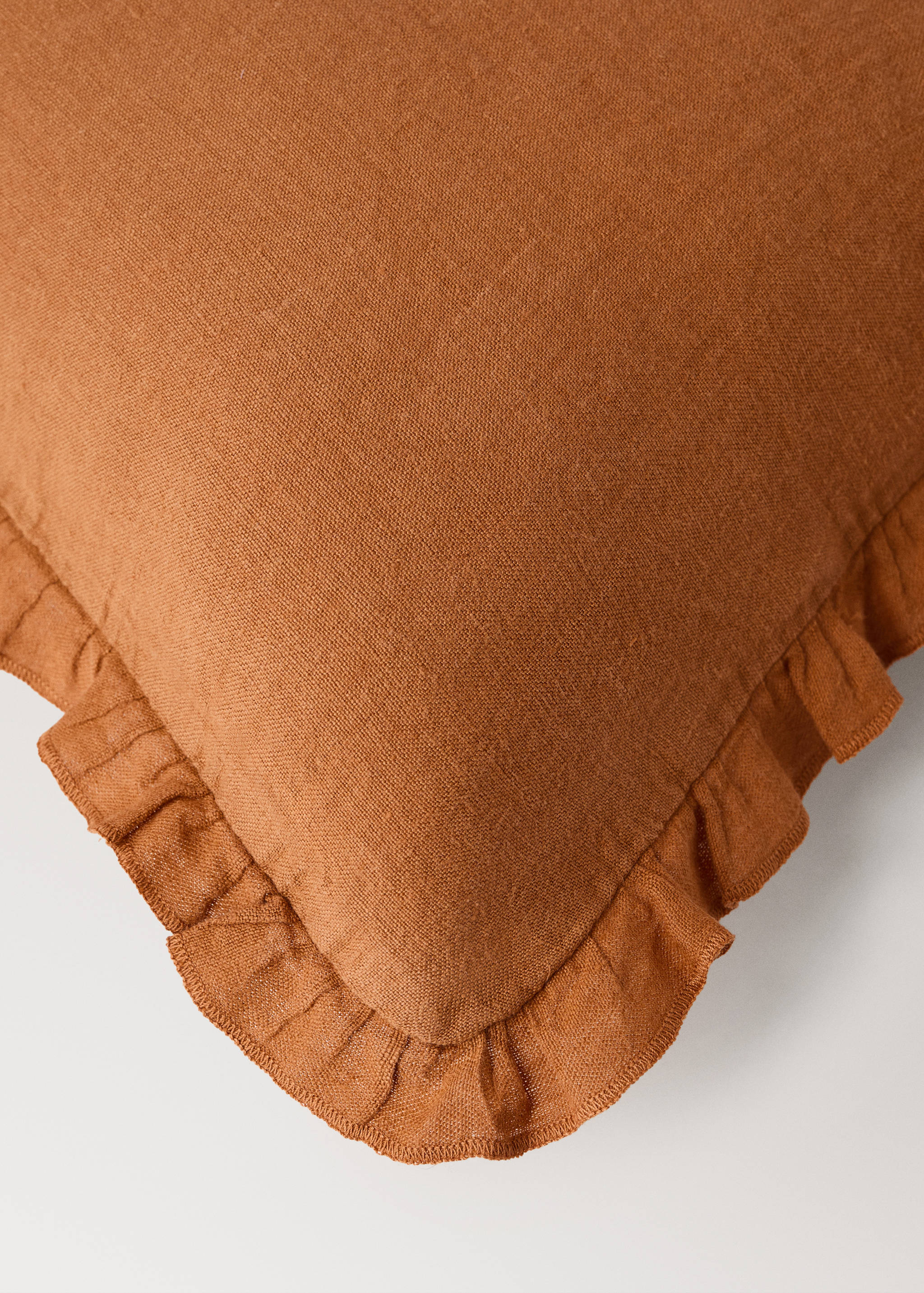 Terracotta cushion cover with a ruffled trim and woven texture.