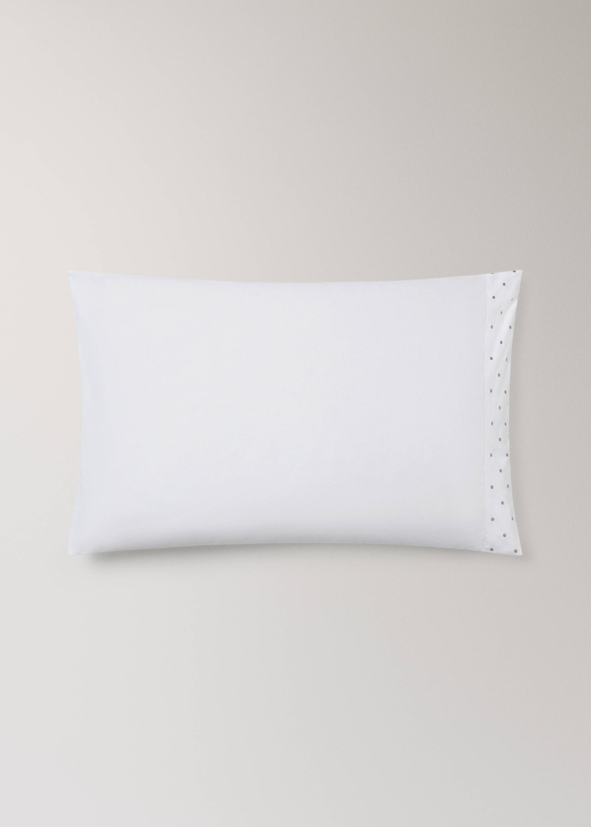 Funda de almohada blanca con una banda con motivo de plumeti en el borde derecho.