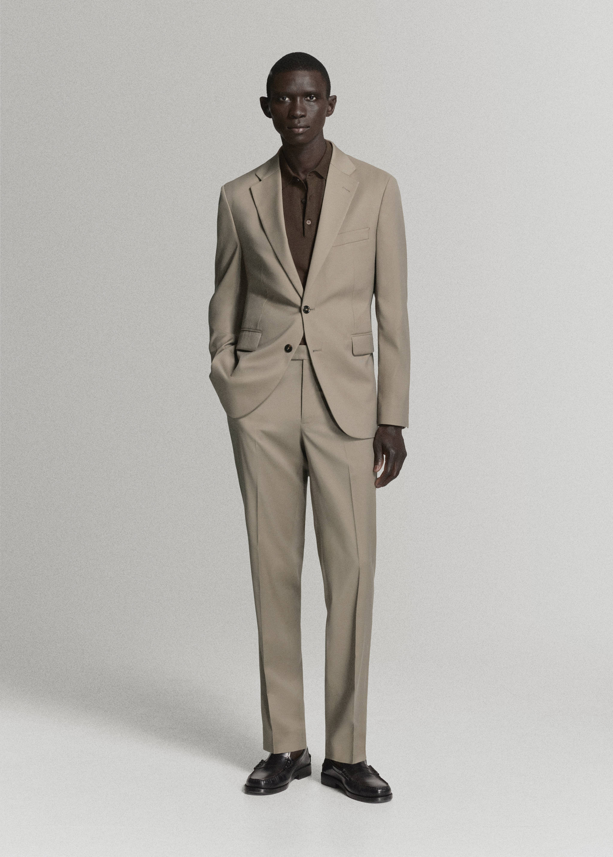 Beige trousers with matching suit jacket and dark brown polo shirt.