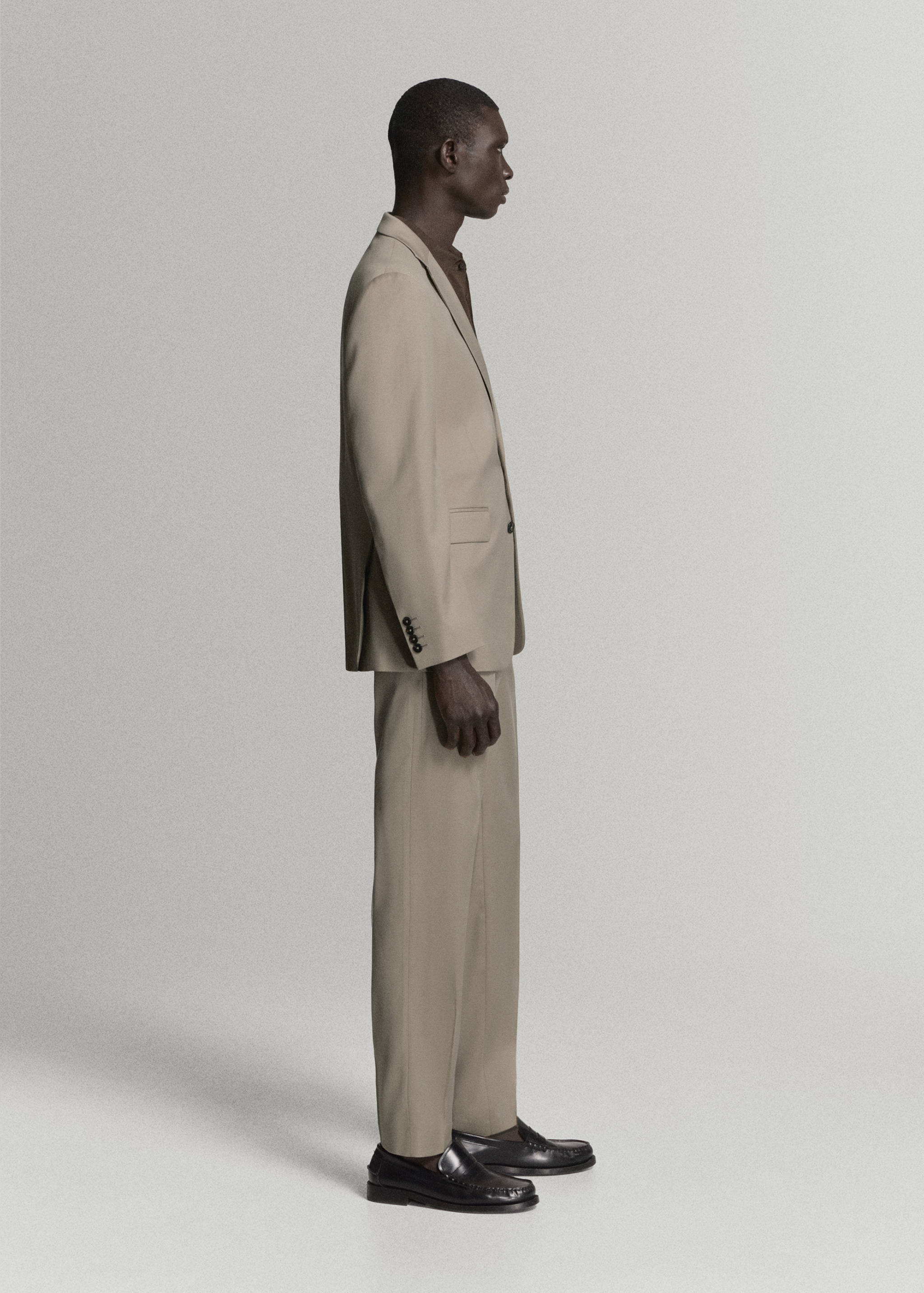 Beige trousers in a straight fit, worn with a matching blazer and black loafers.