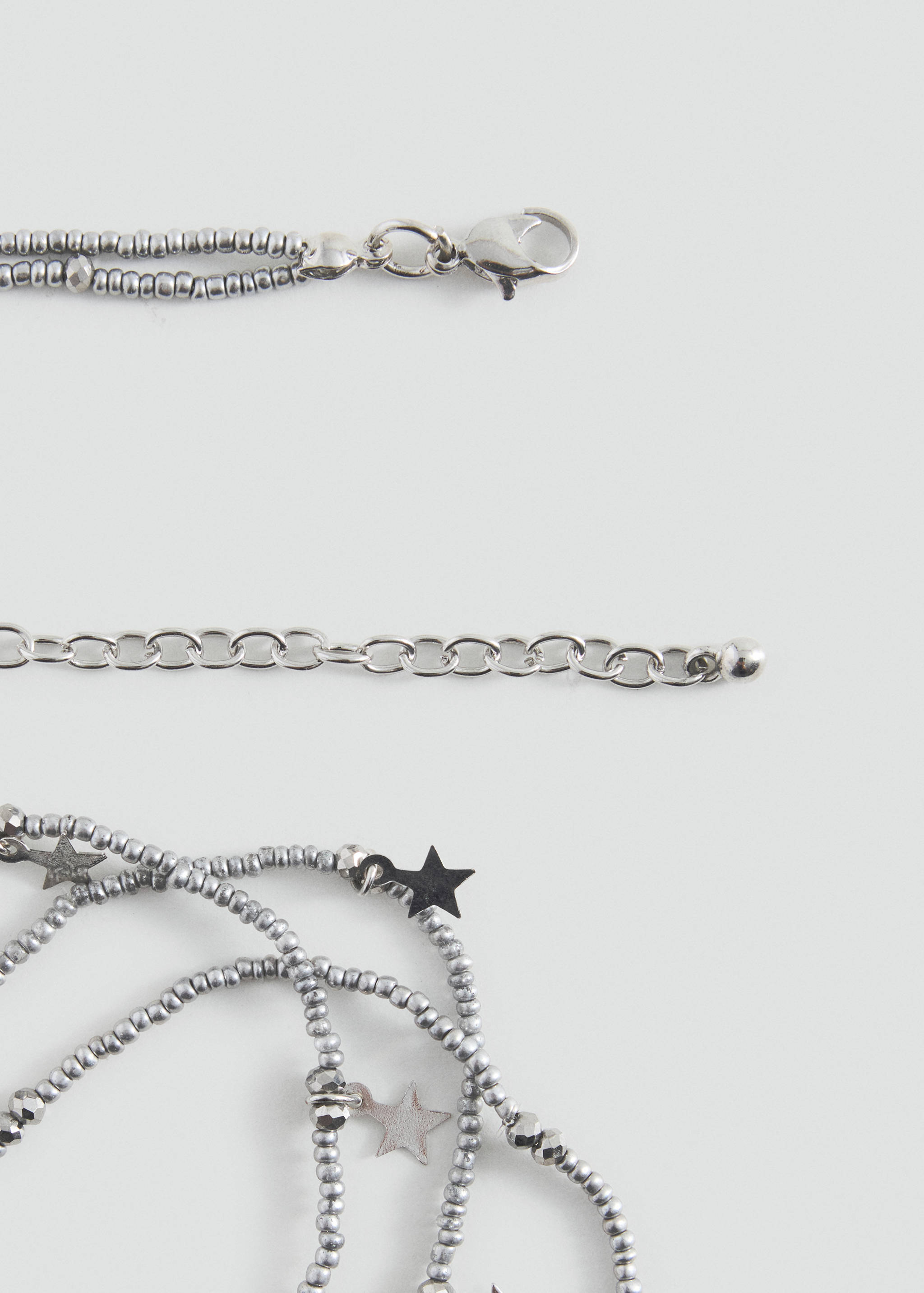 Close-up of a silver-toned beaded necklace with star charms and adjustable clasp.