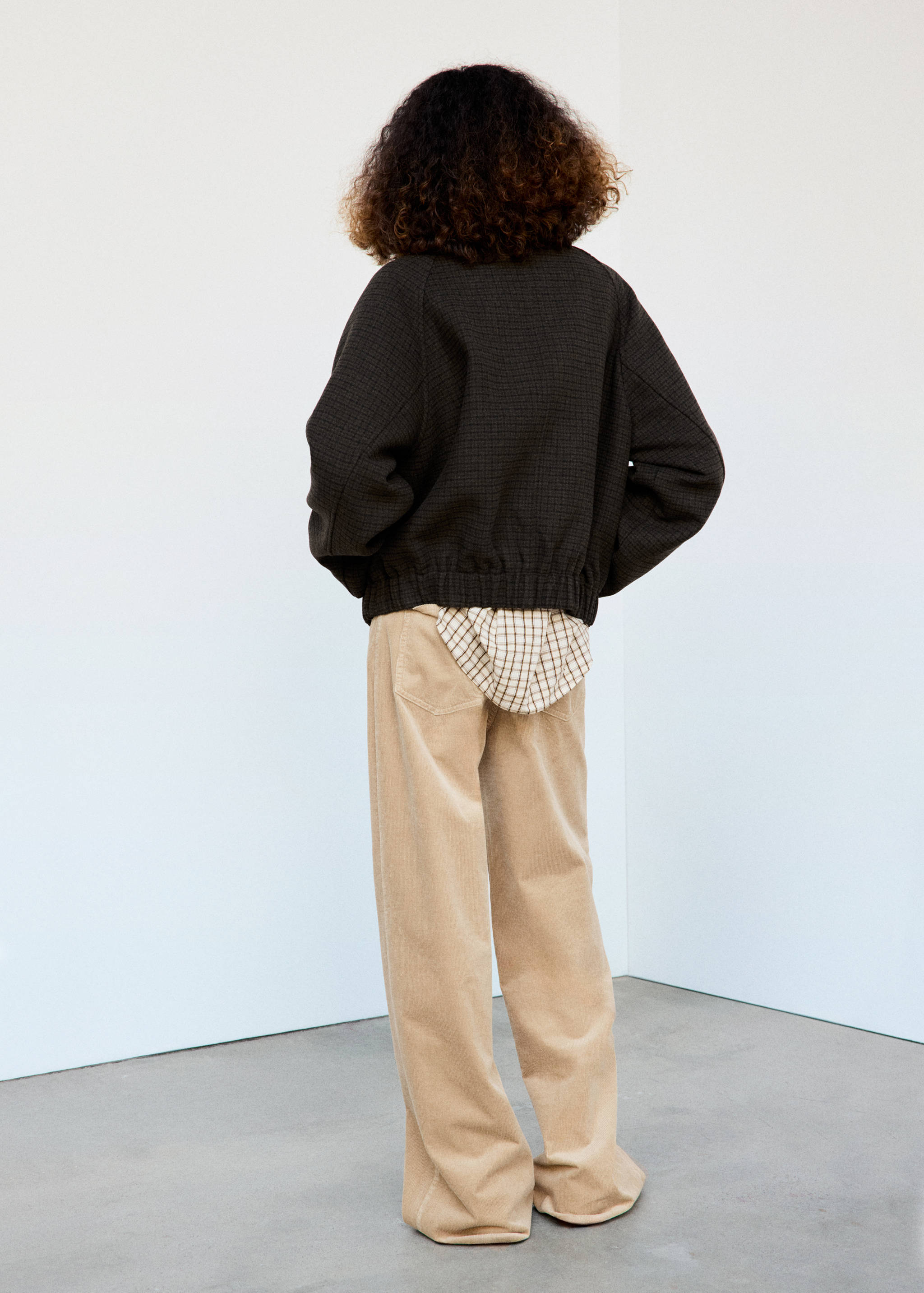 Dark brown textured jacket with a ribbed hem, seen from the back.