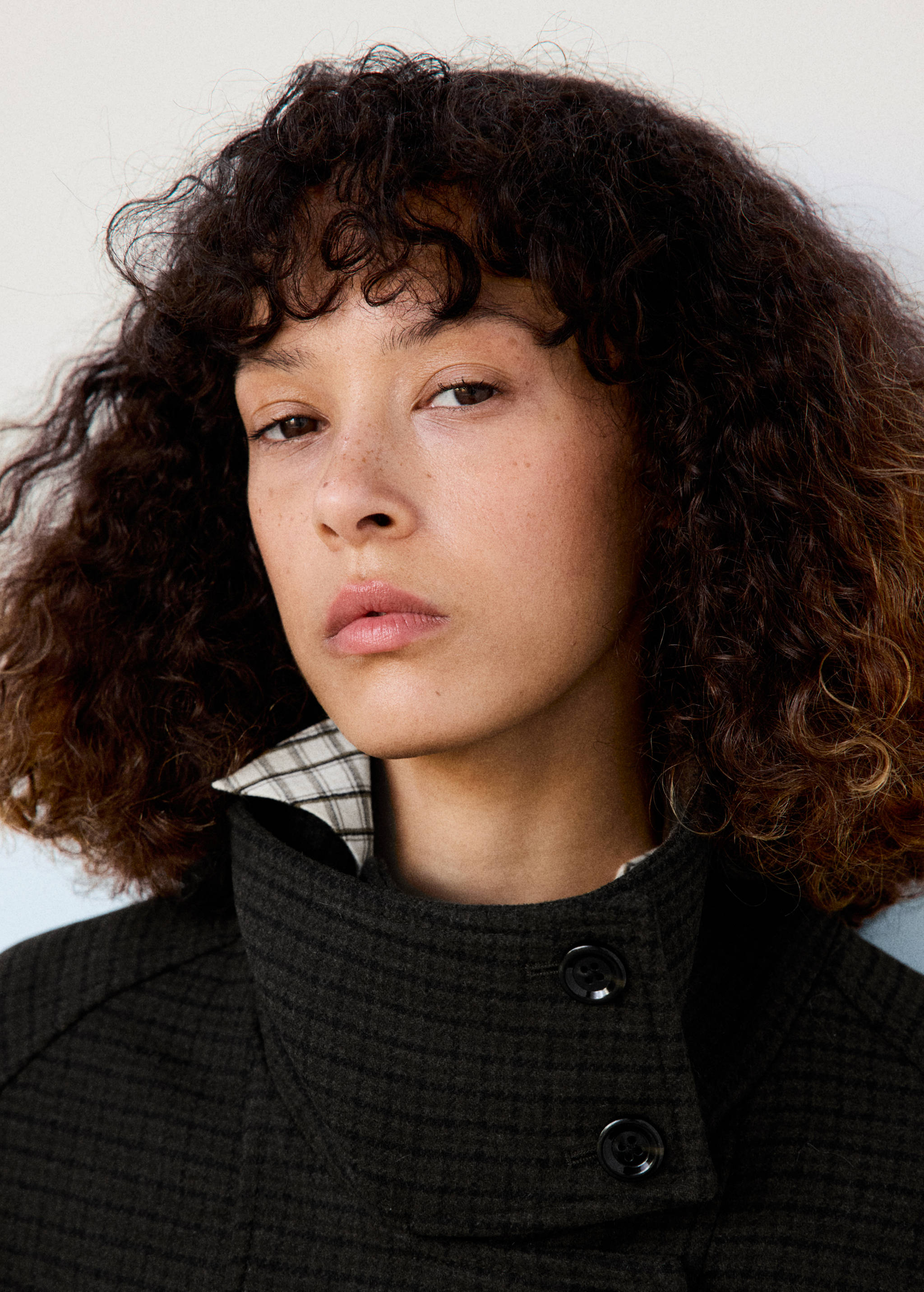 Close-up of a model wearing a dark patterned jacket with a high collar.