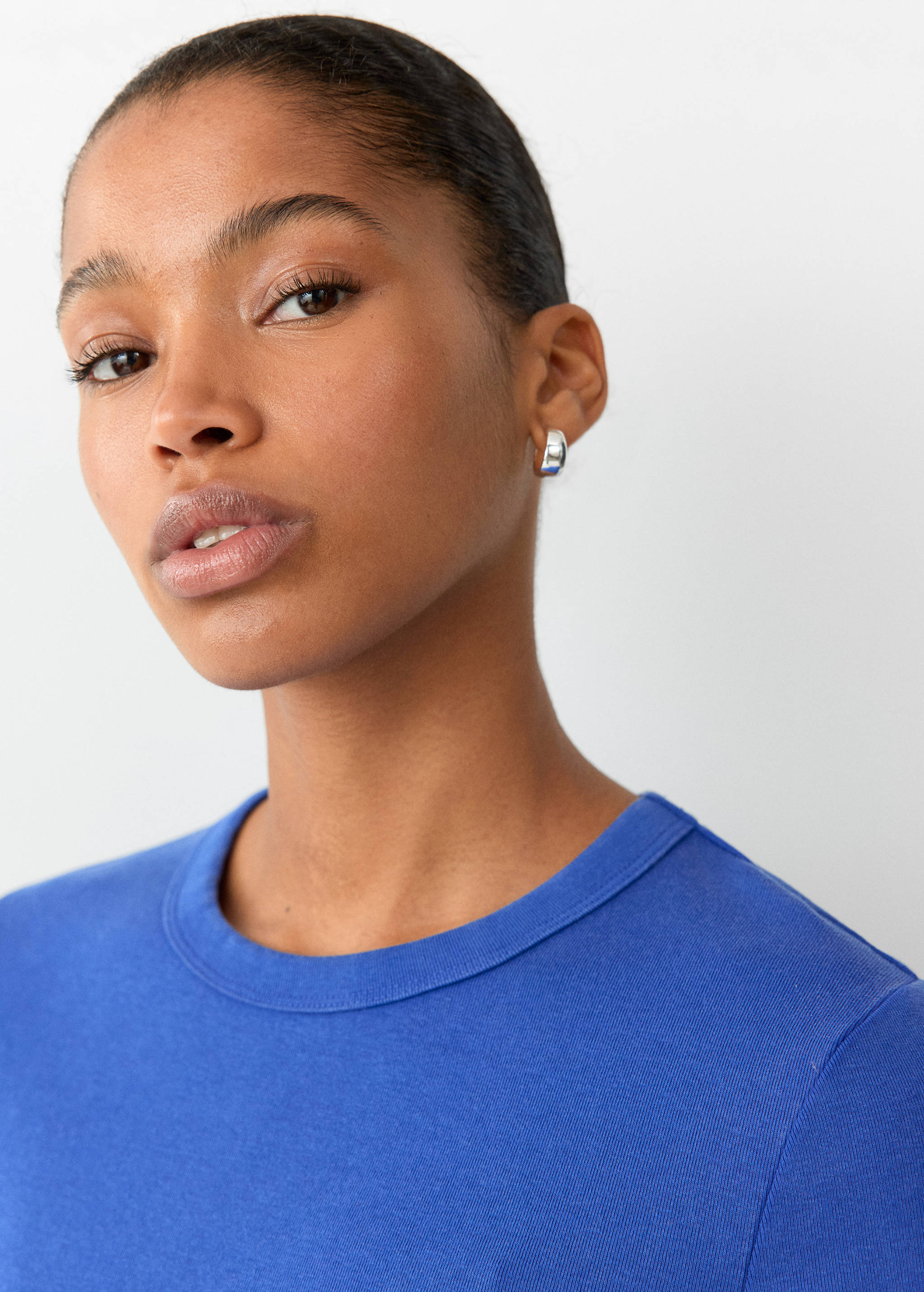 Close-up of a blue t-shirt with a round neckline worn by a model.