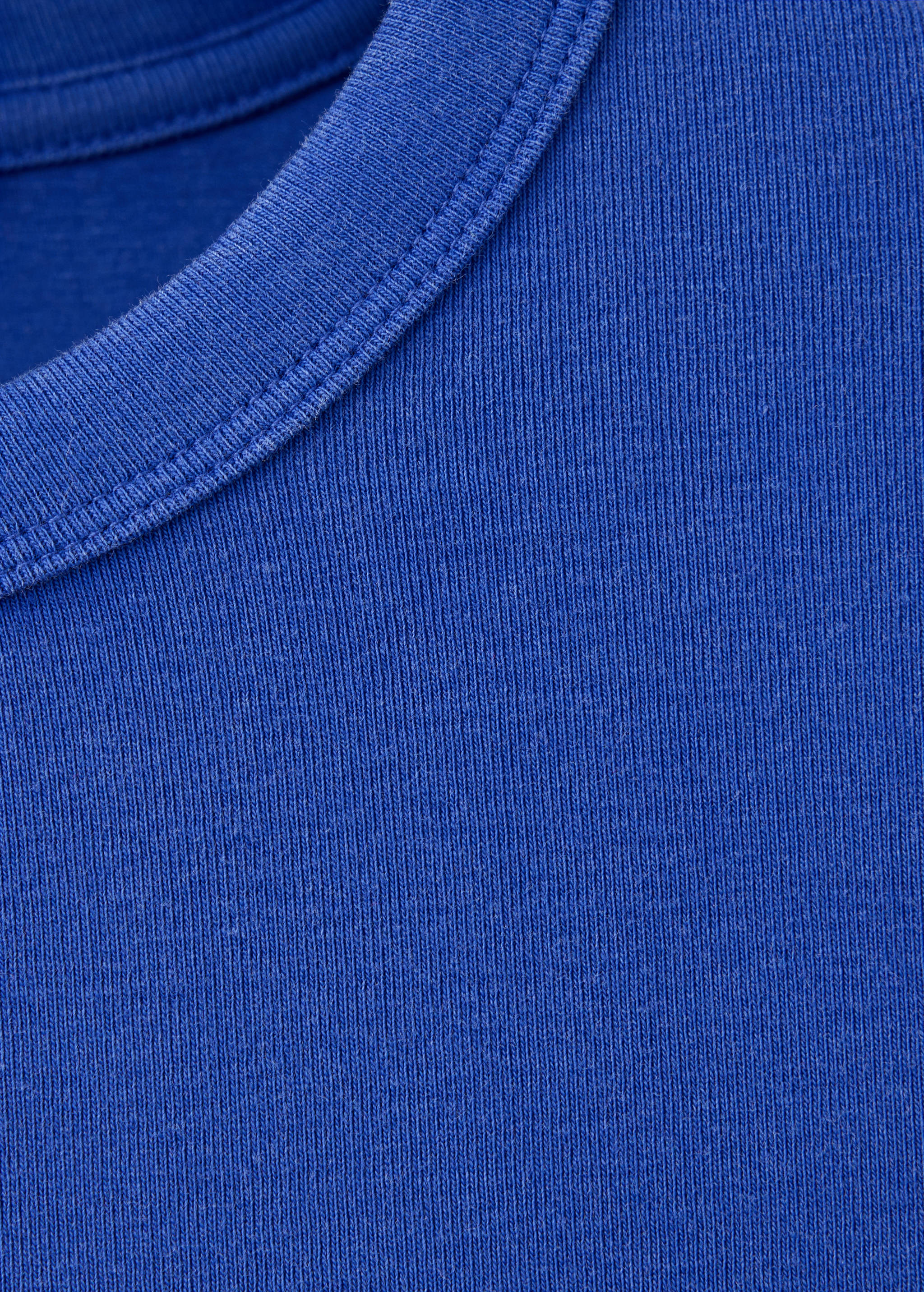 Blue t-shirt detail showing the ribbed round neckline.