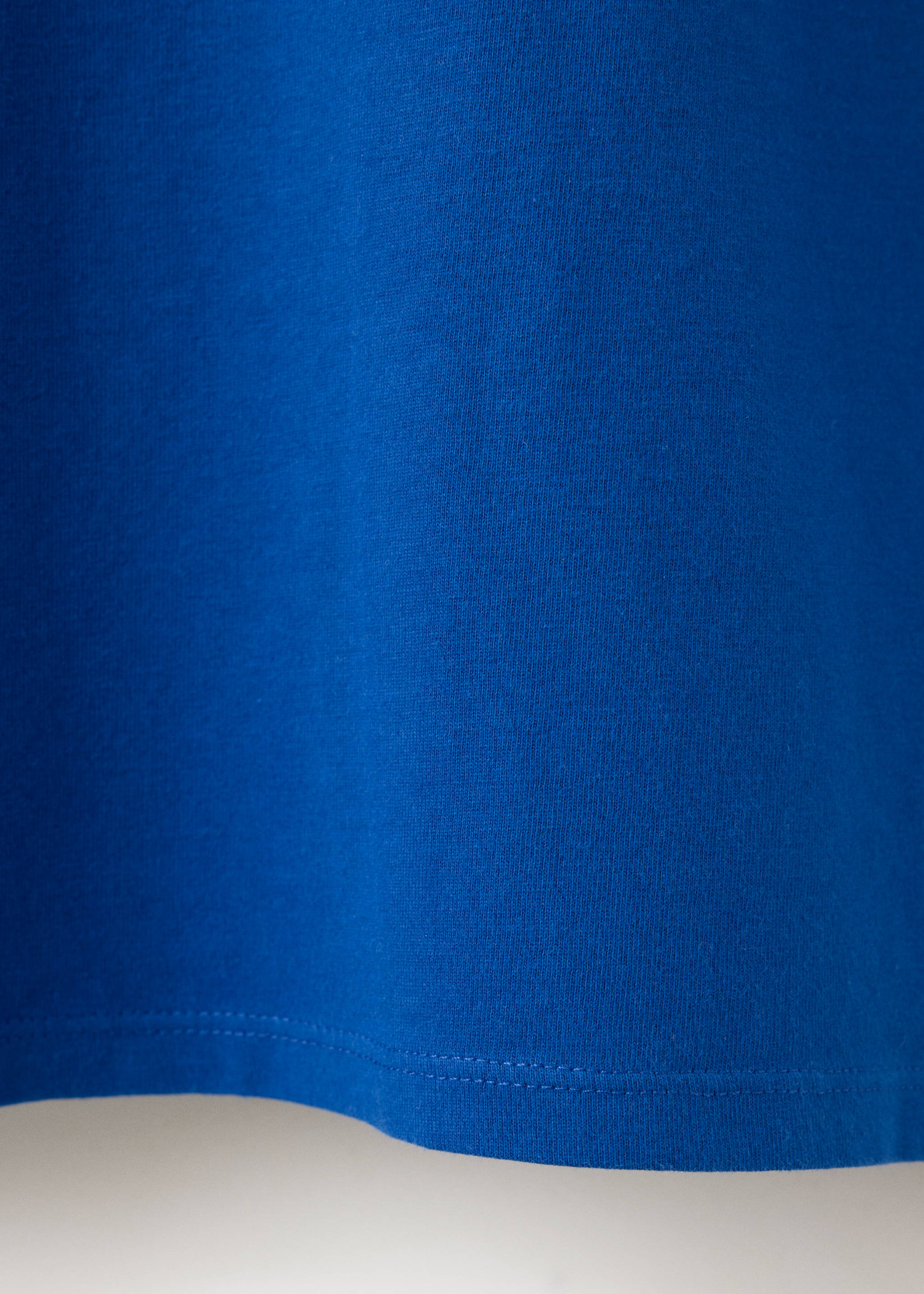 Close-up of the blue t-shirt fabric and hem texture.