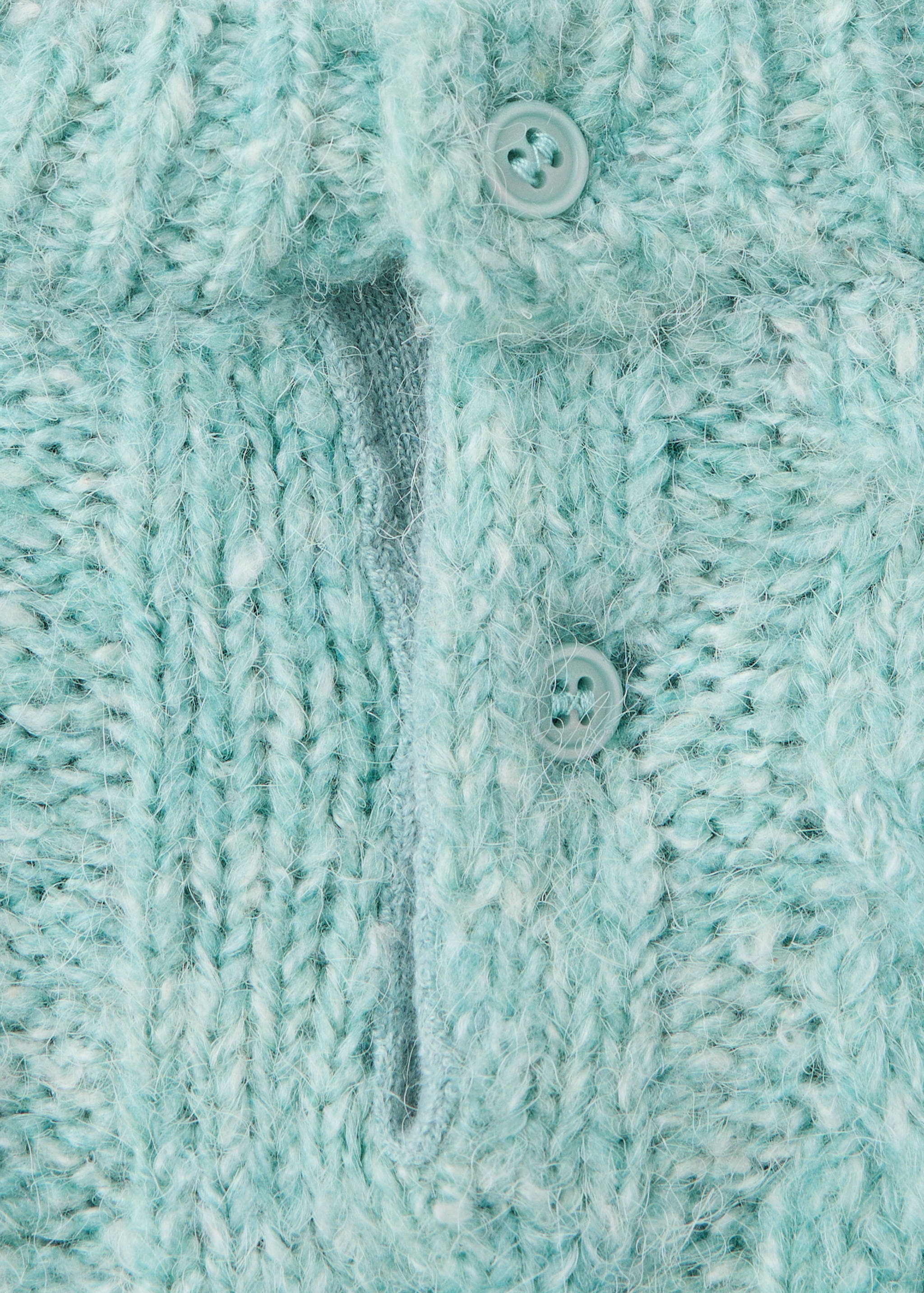 Close-up of a light turquoise knitted jersey showing its fuzzy texture and button placket.