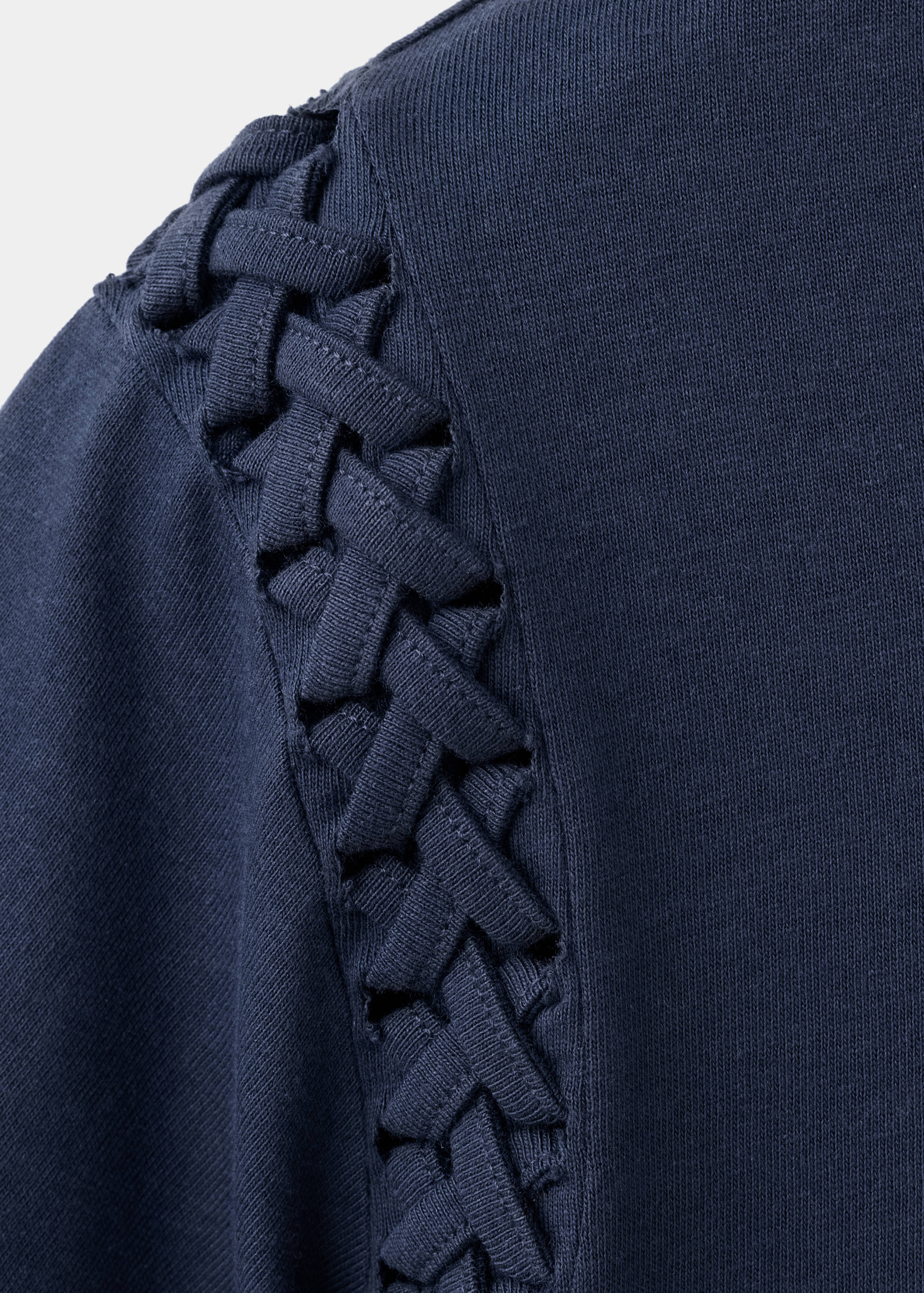 Close-up of navy t-shirt featuring woven braided shoulder detail.