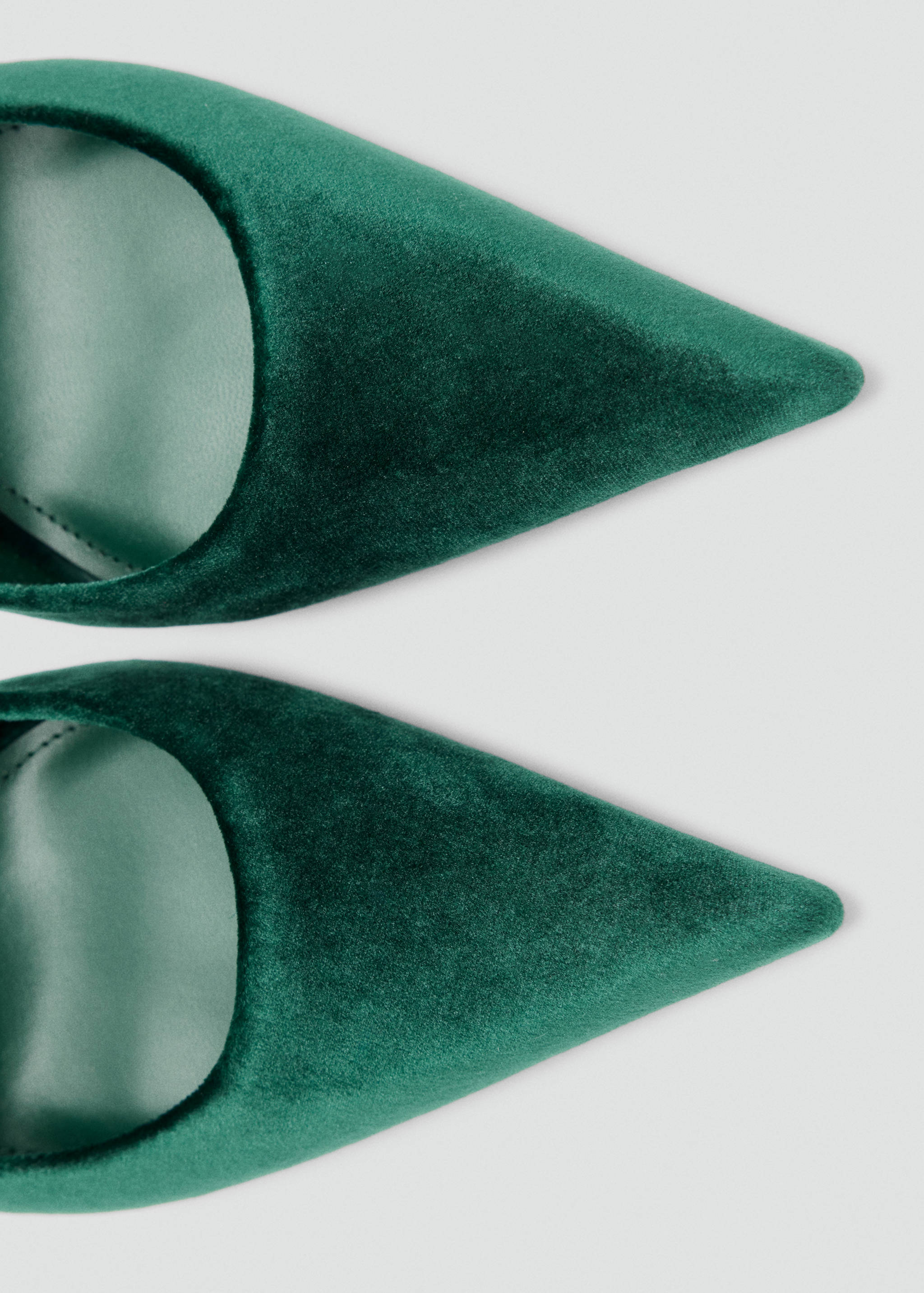 Close-up of dark green velvet shoes with a pointed toe.