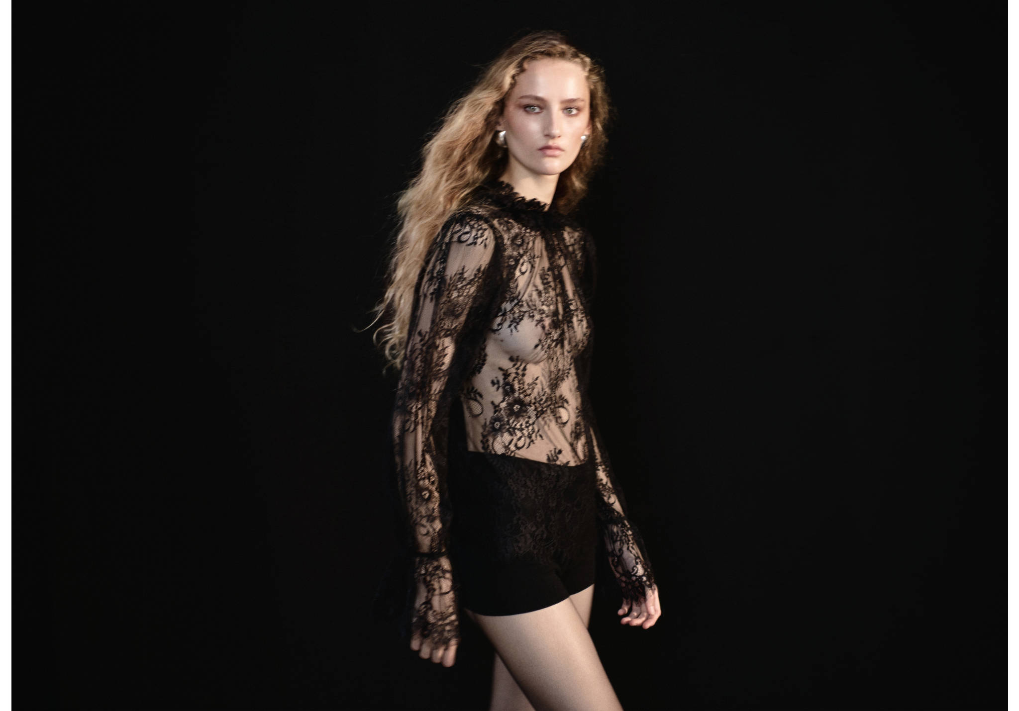 Black lace blouse with a high ruffled collar and long sleeves.