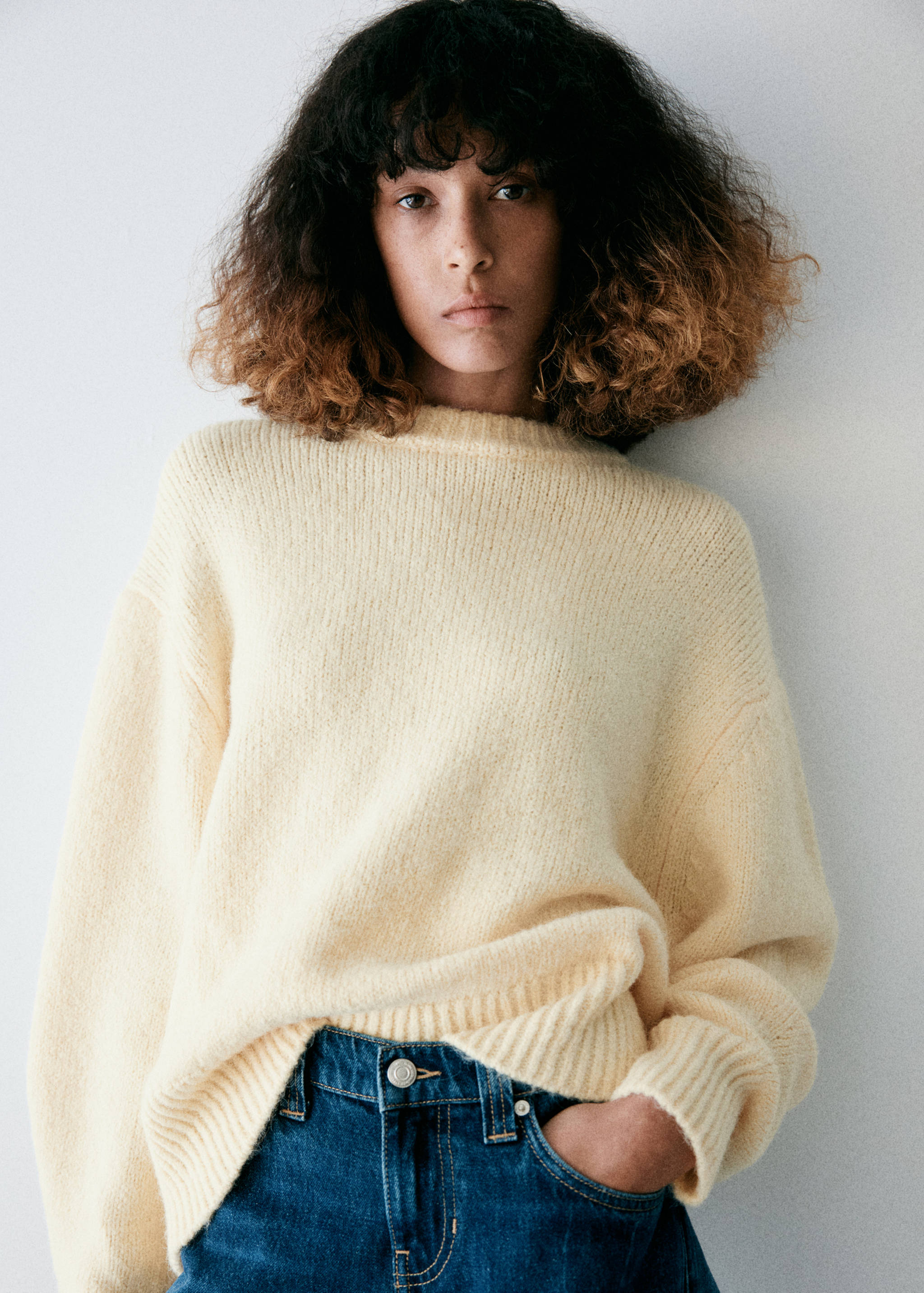 Pale yellow knitted jersey with a ribbed crew neck and long sleeves.