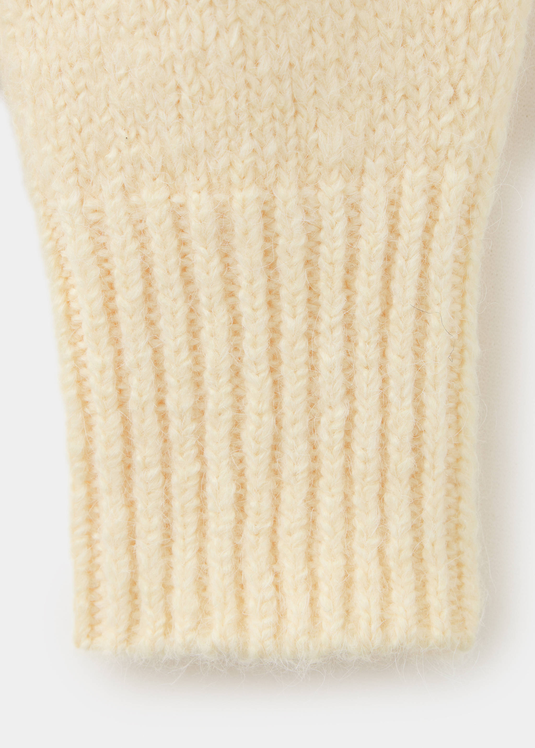 Close-up of the ribbed cuff and fuzzy knit texture of a cream jersey.