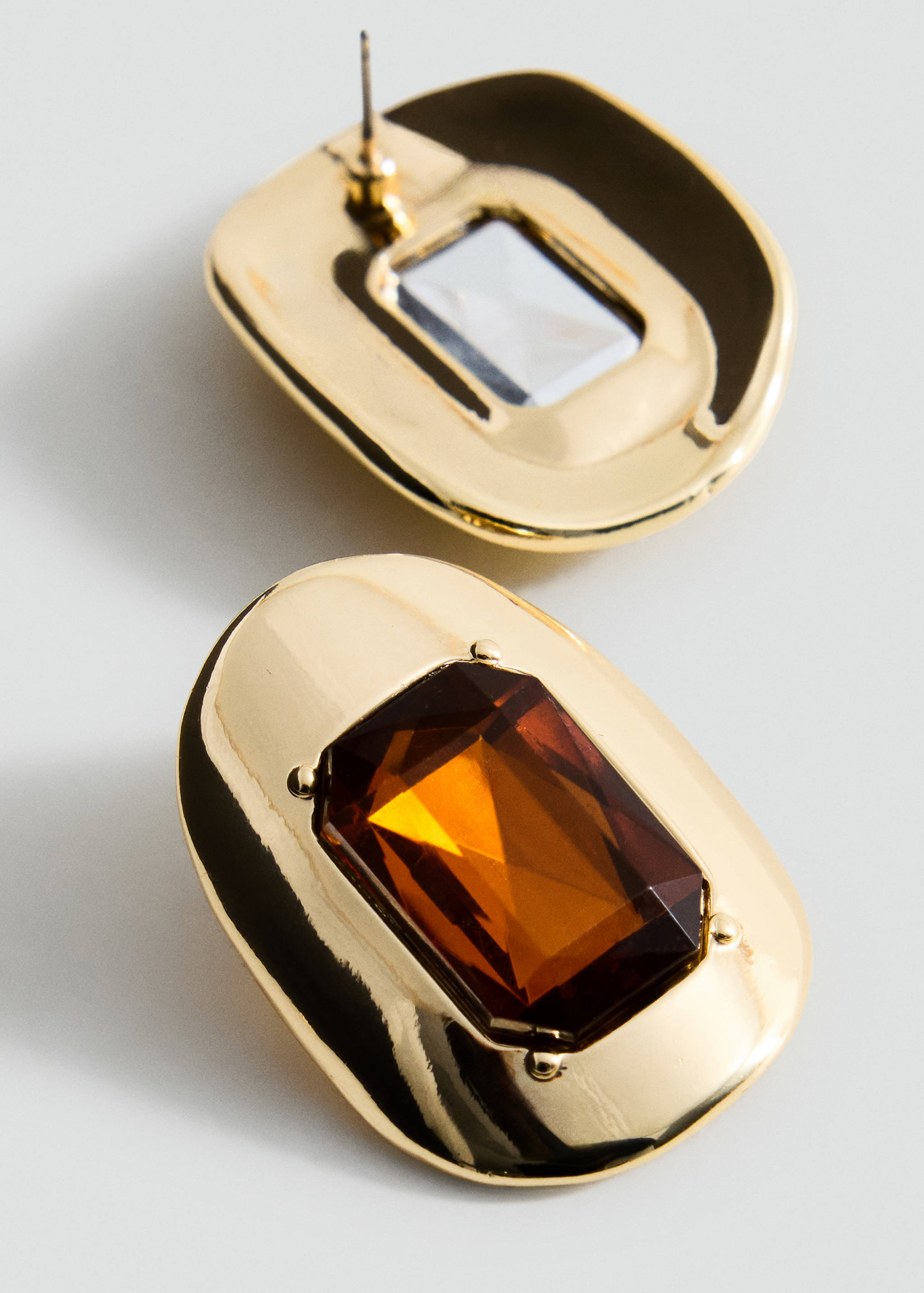 Gold earrings featuring a smooth geometric shape with a central faceted amber-brown stone.