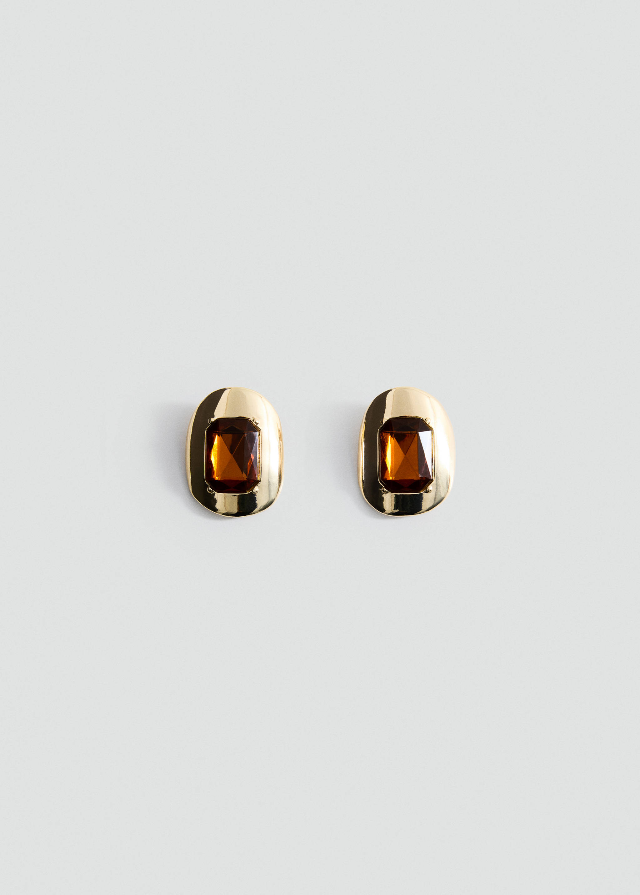 Gold-finish metal earrings with faceted amber-coloured stones in a still-life view.
