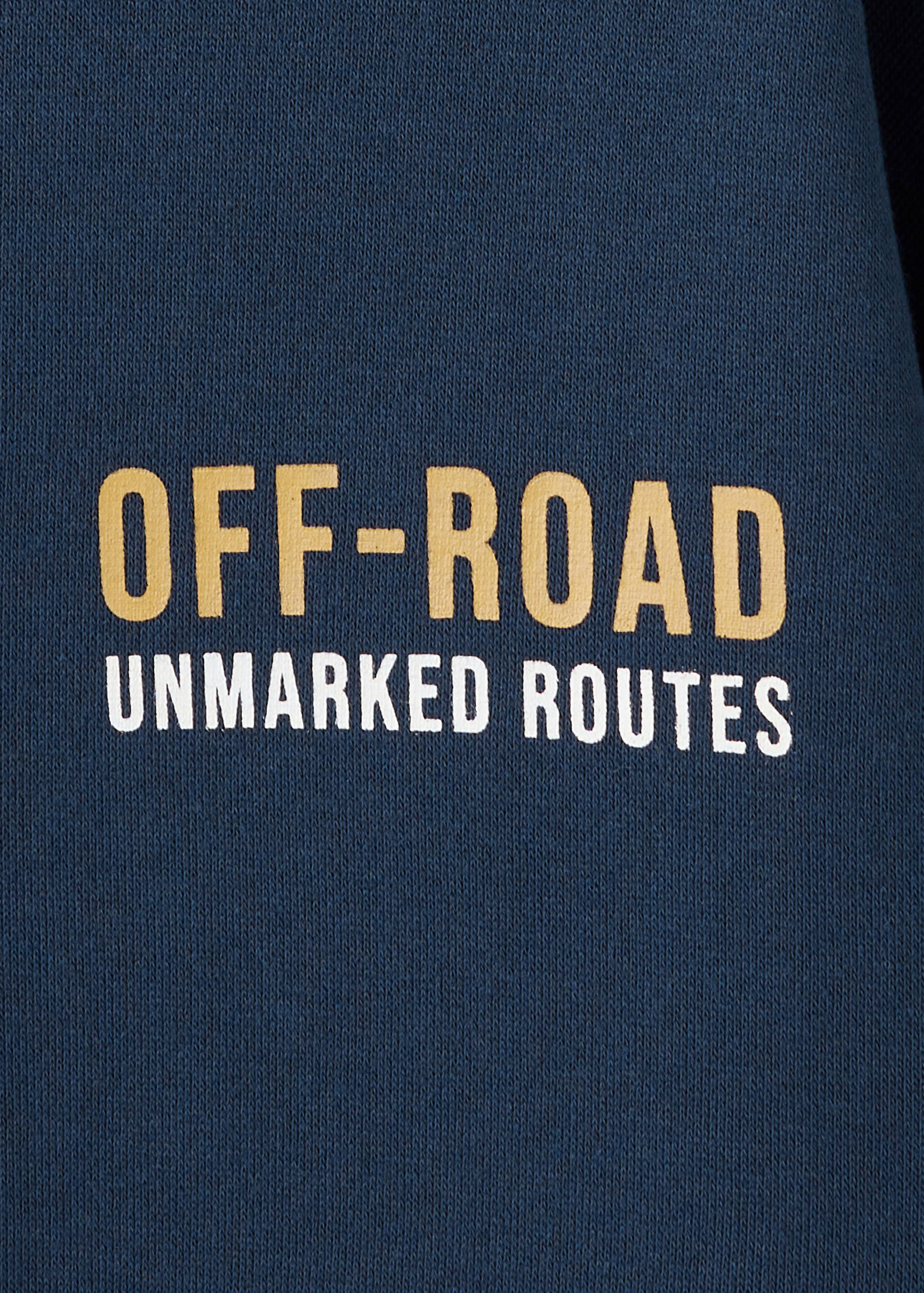 Close-up of a blue sweatshirt with 'OFF-ROAD UNMARKED ROUTES' text.