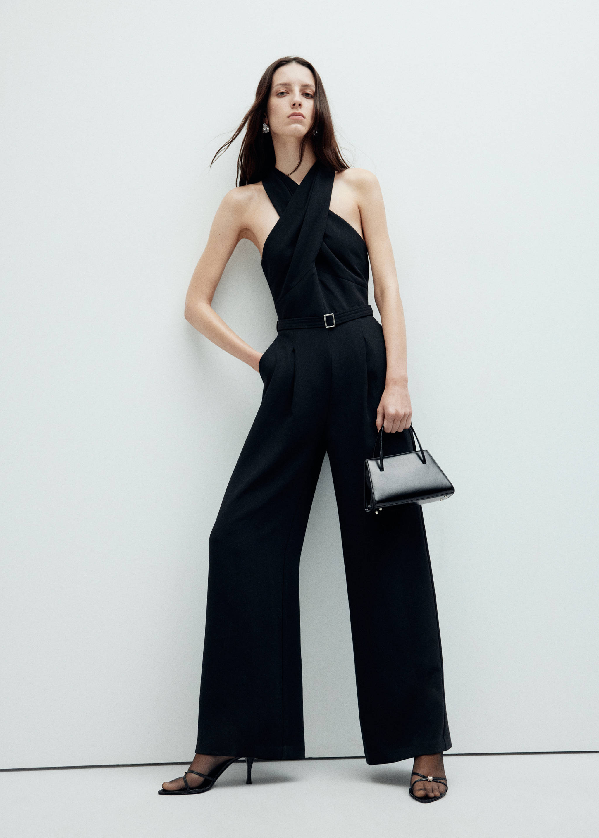 Black halter-neck jumpsuit with a crossed wrap bodice and matching belt.
