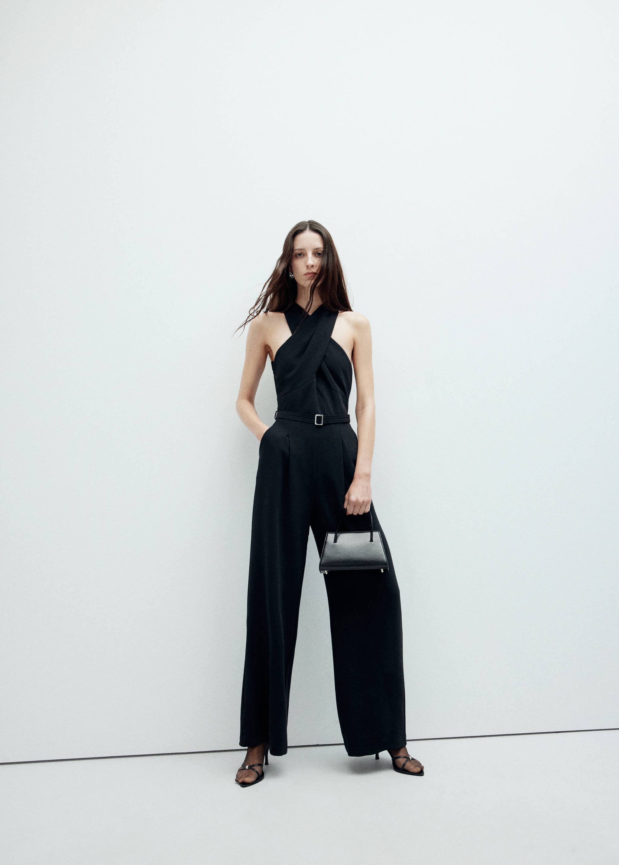 Black halter-neck jumpsuit with a thin buckled belt and wide legs.