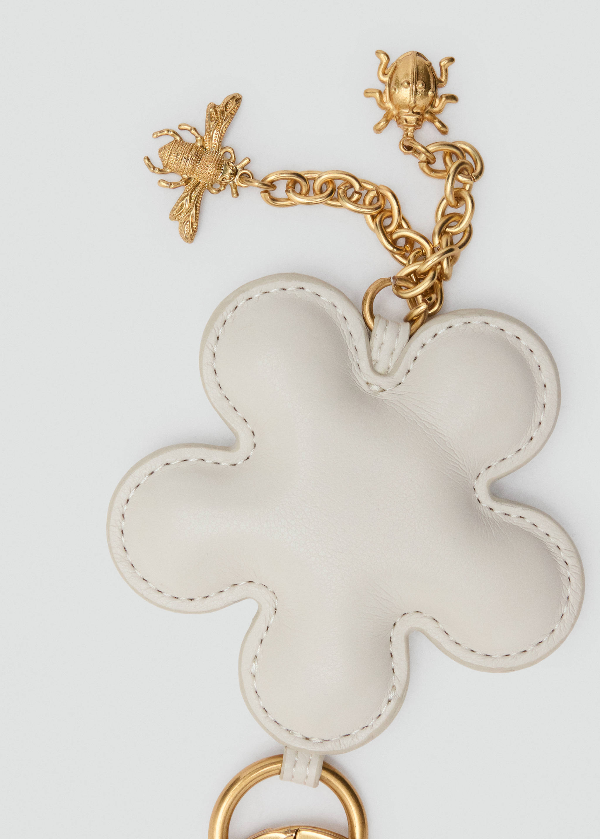 Off-white padded flower-shaped keychain with gold bee and ladybug charms.