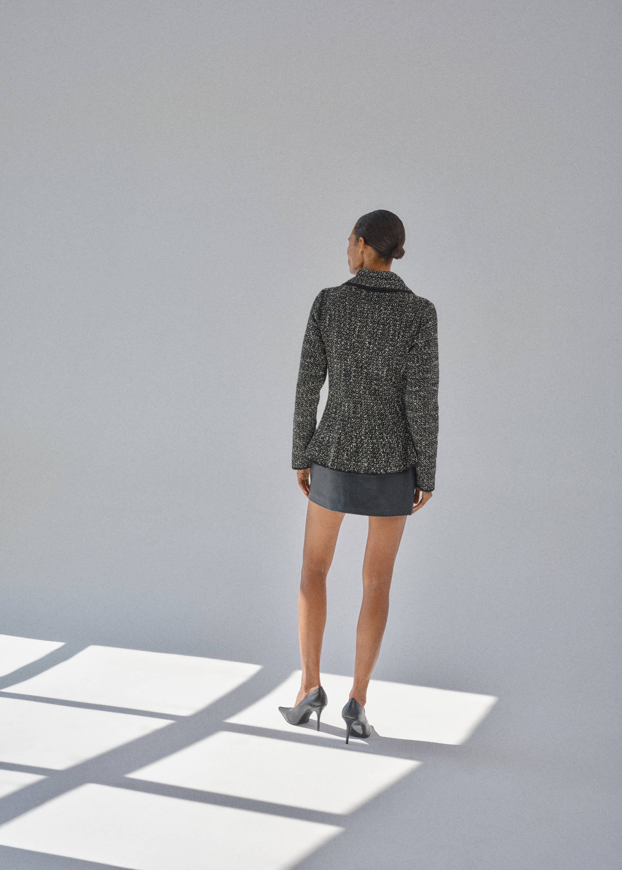 Black and white tweed jacket with a peplum waist, shown from the back.