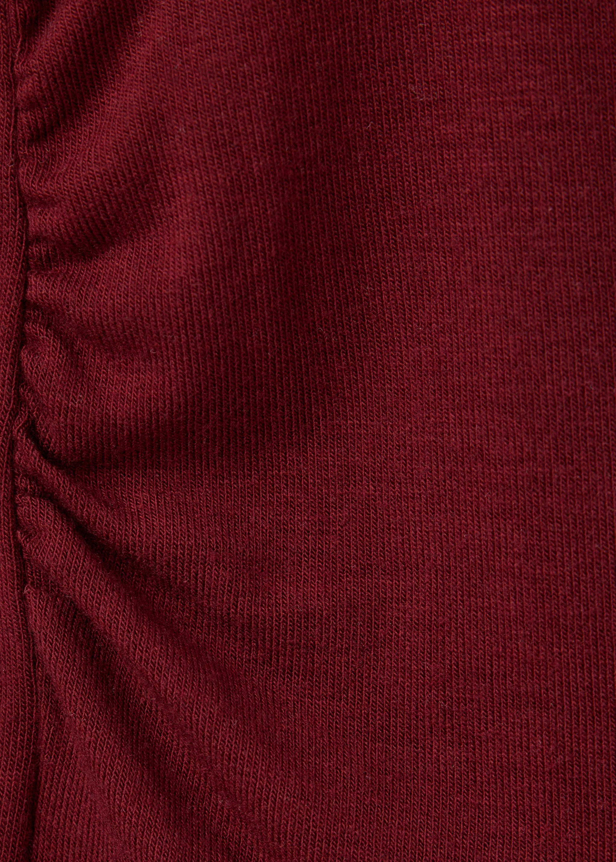 Close-up of a dark red t-shirt with ruched side detail.