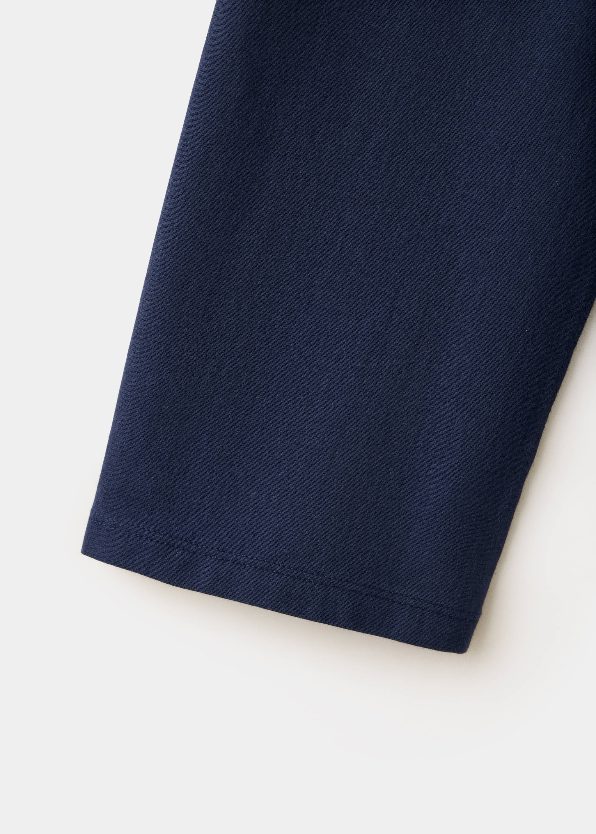 Close-up of navy blue t-shirt fabric and sleeve hem detail.