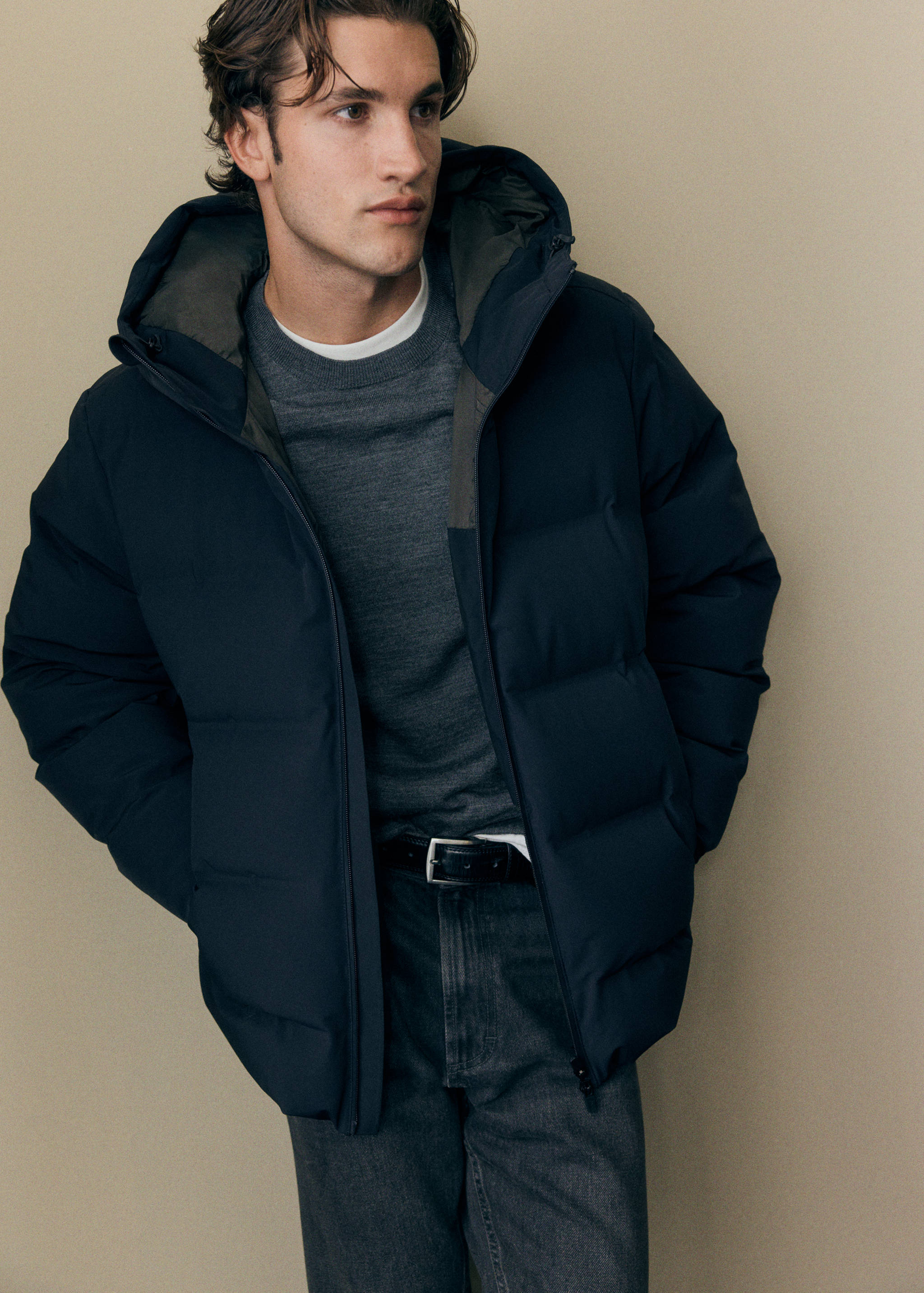 Navy blue quilted anorak with hood worn over a grey sweater.