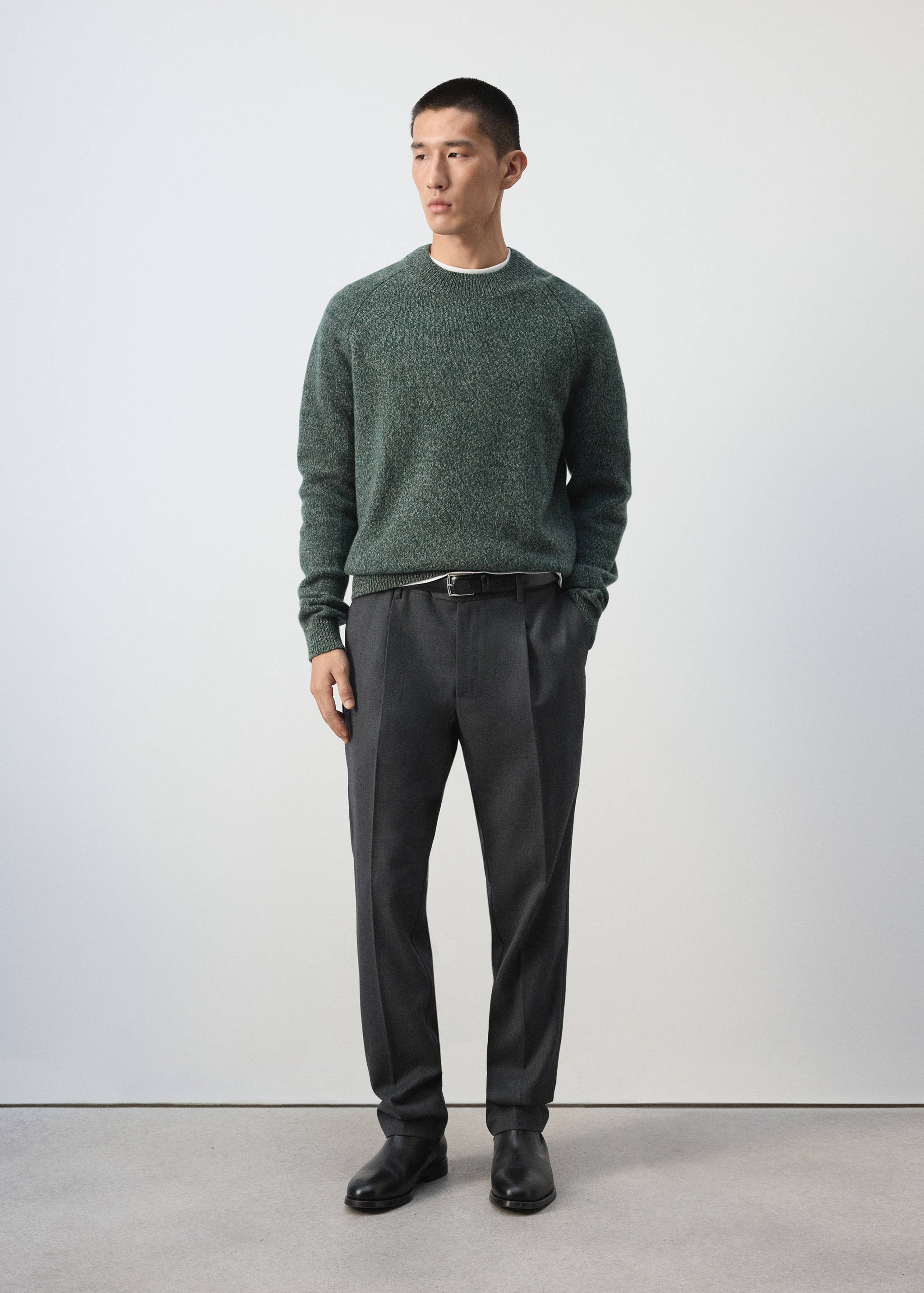 Green melange knit jersey with a crew neckline worn with trousers.