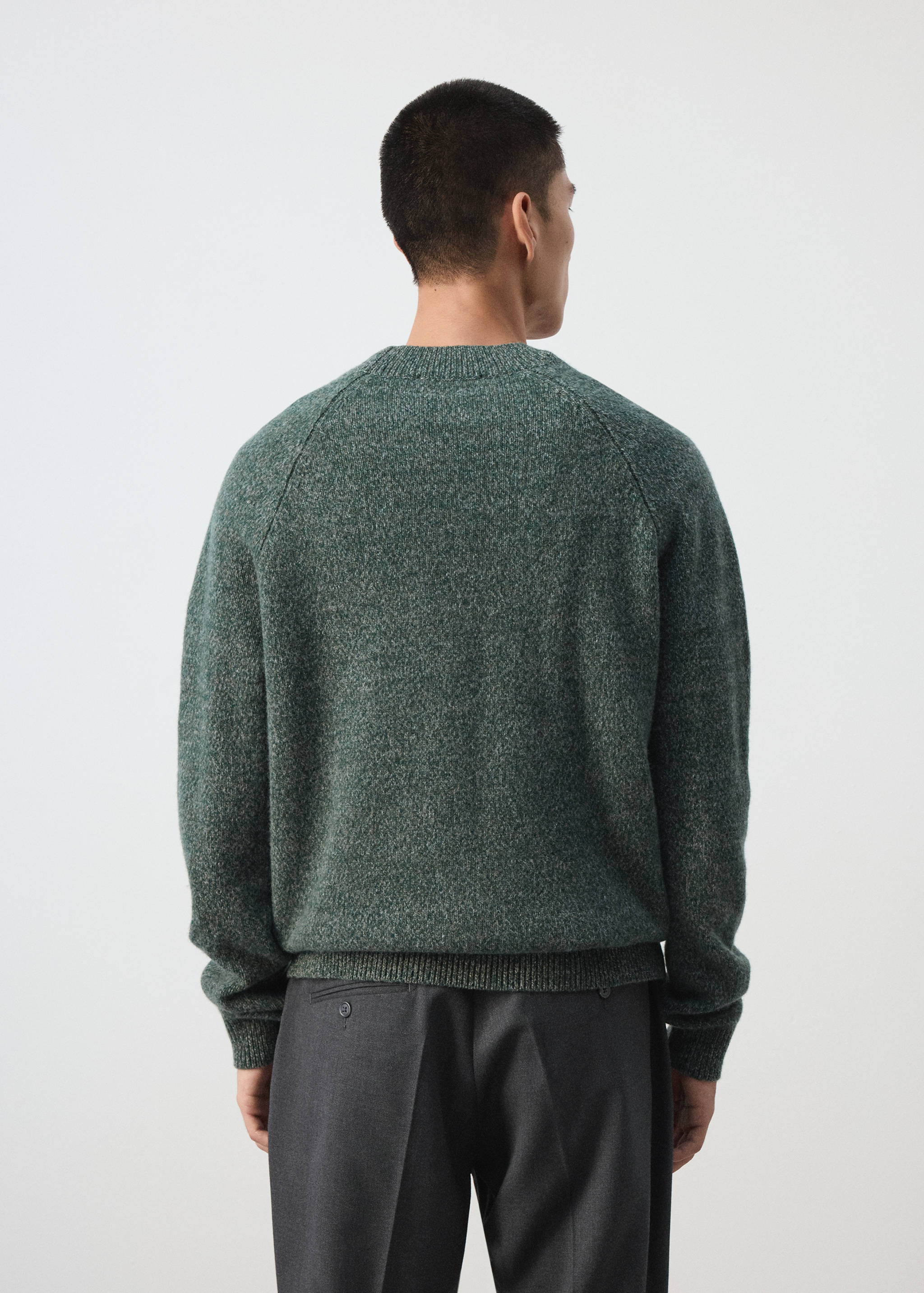 Back view of a dark green melange knit sweater with raglan sleeves.