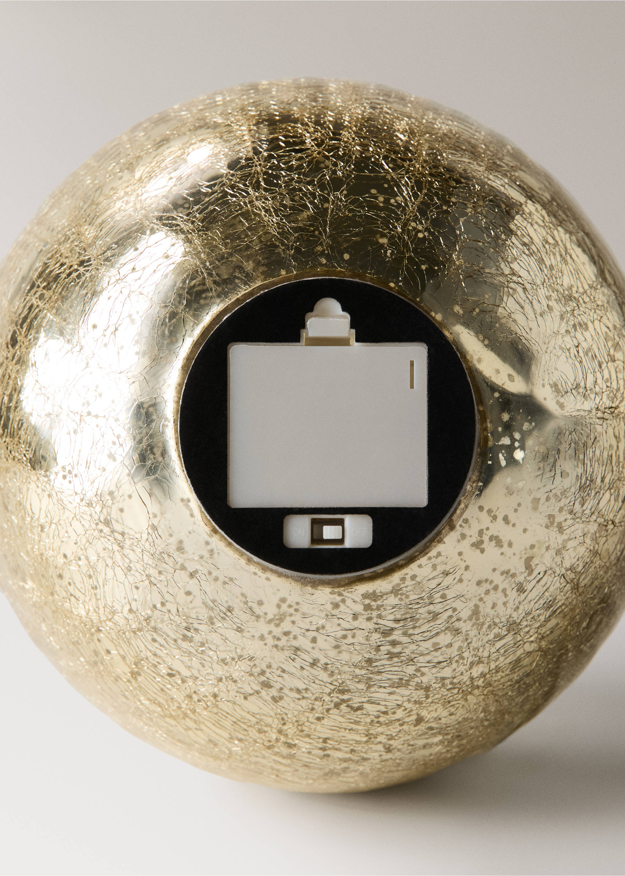 Detail of a gold crackled Christmas ornament showing the battery compartment., Gold. Ref: 37027896-00.