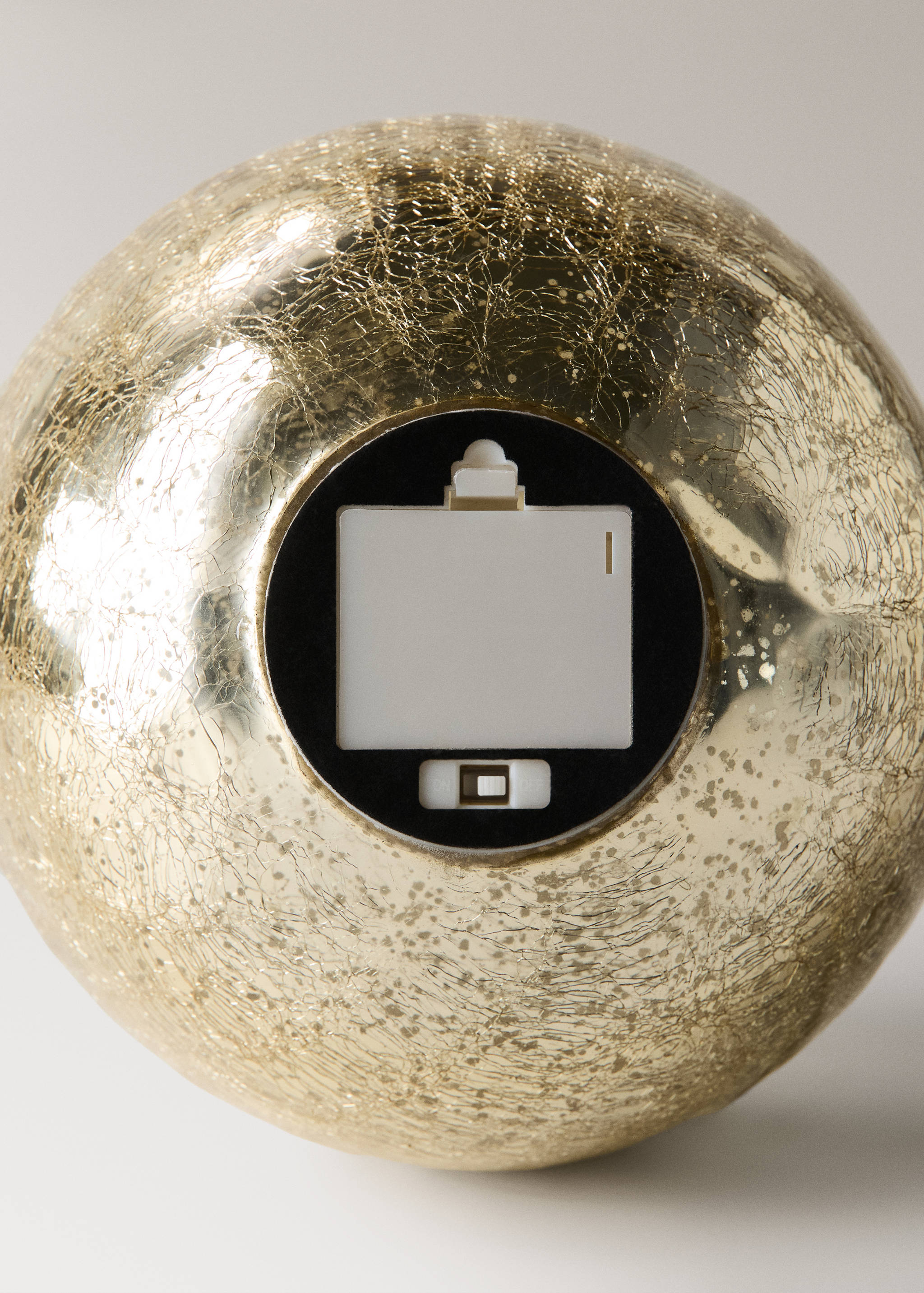 Detail of a gold crackled Christmas ornament showing the battery compartment.
