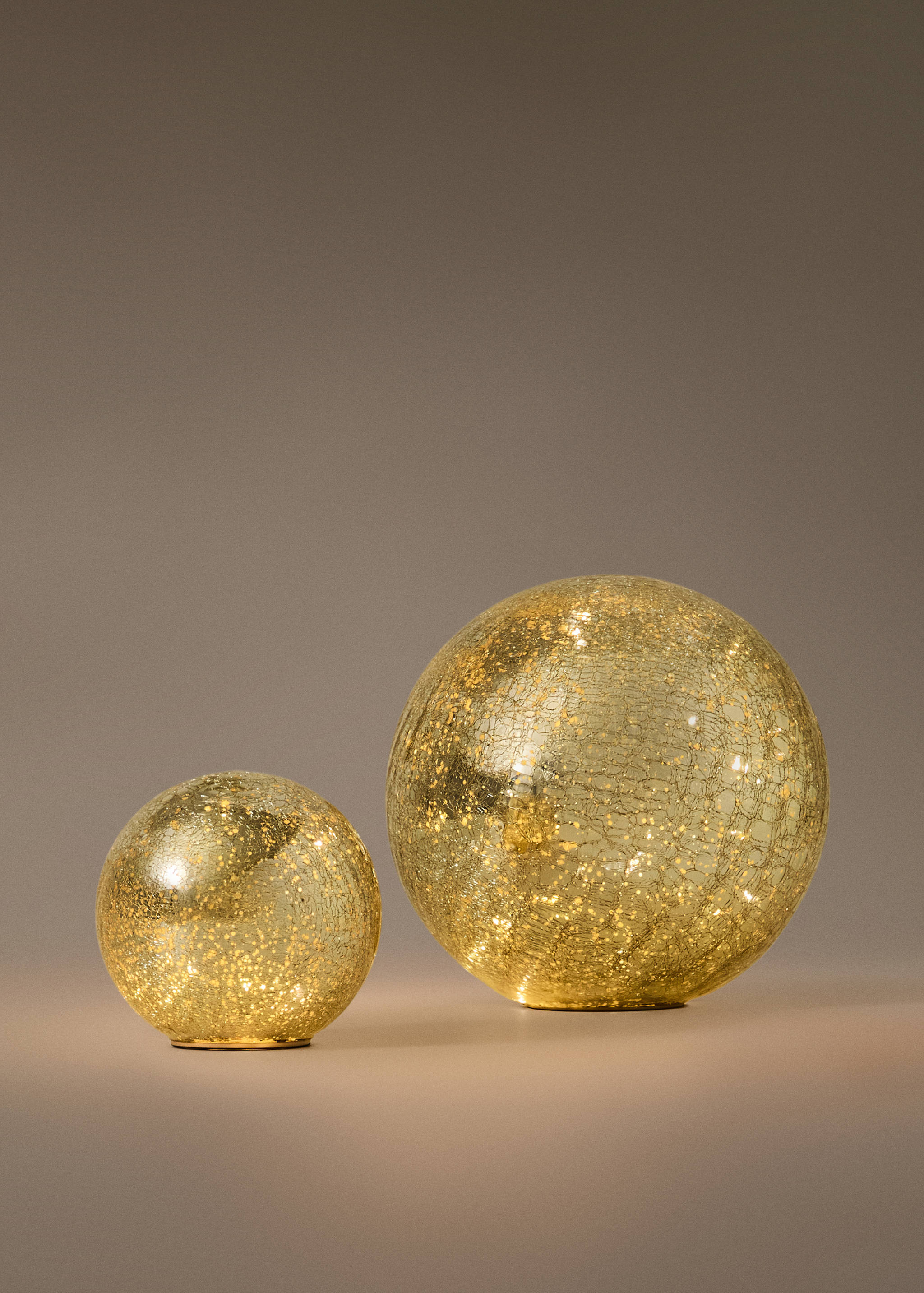 Two gold crackled glass Christmas decoration spheres lit from within.