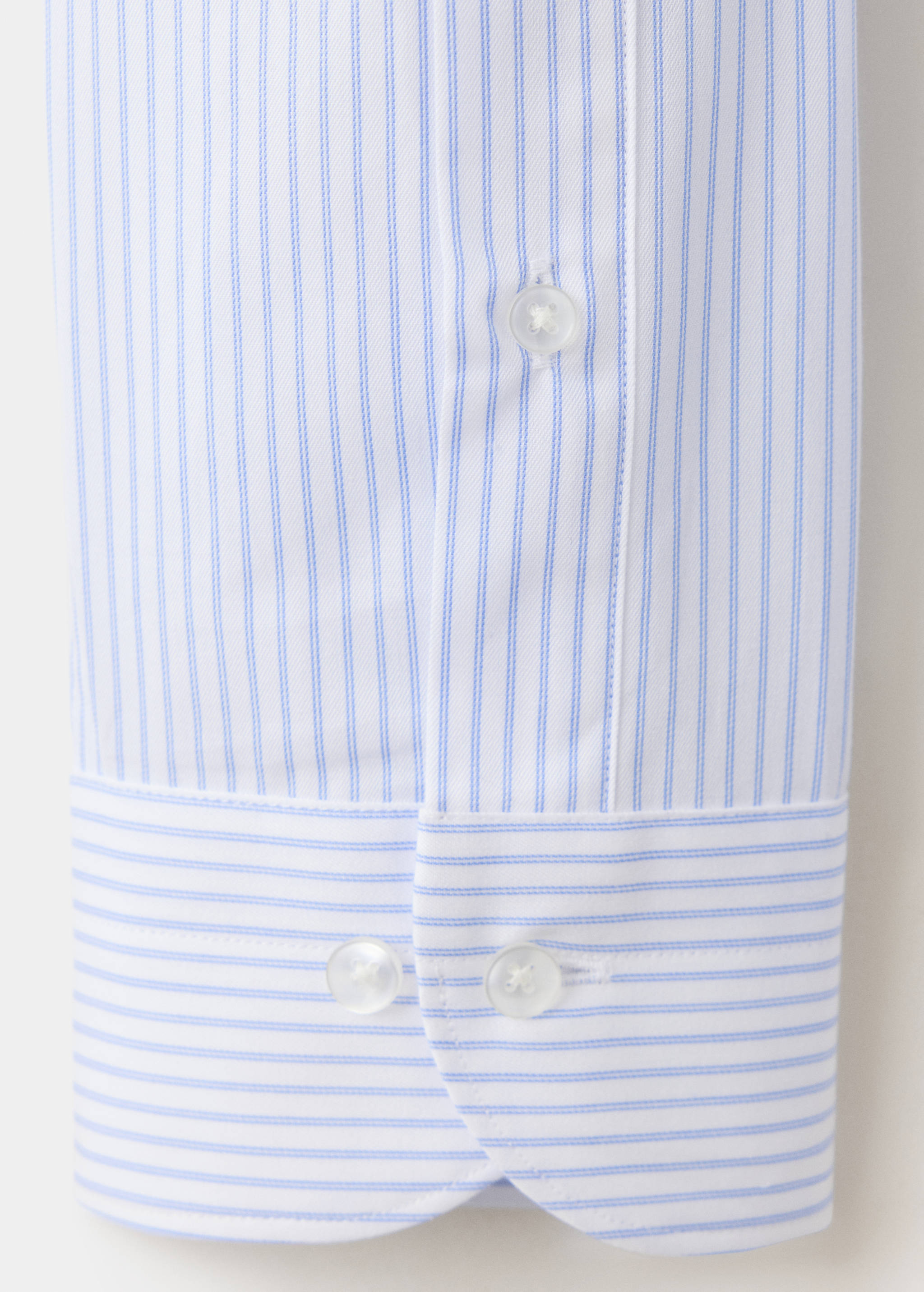 Close-up of a blue and white striped shirt cuff and placket with white buttons.