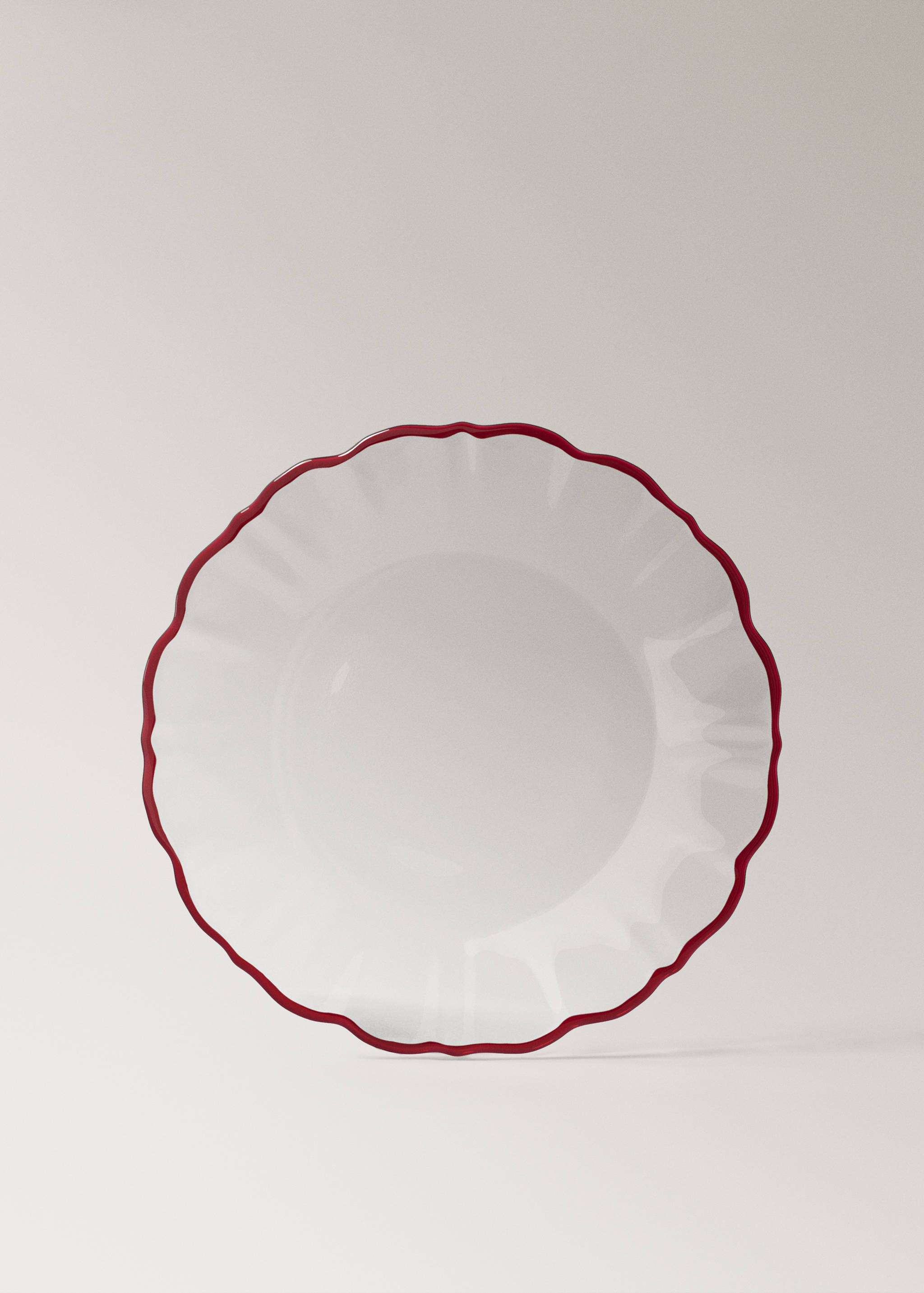Round glass plate with a scalloped edge and red rim.