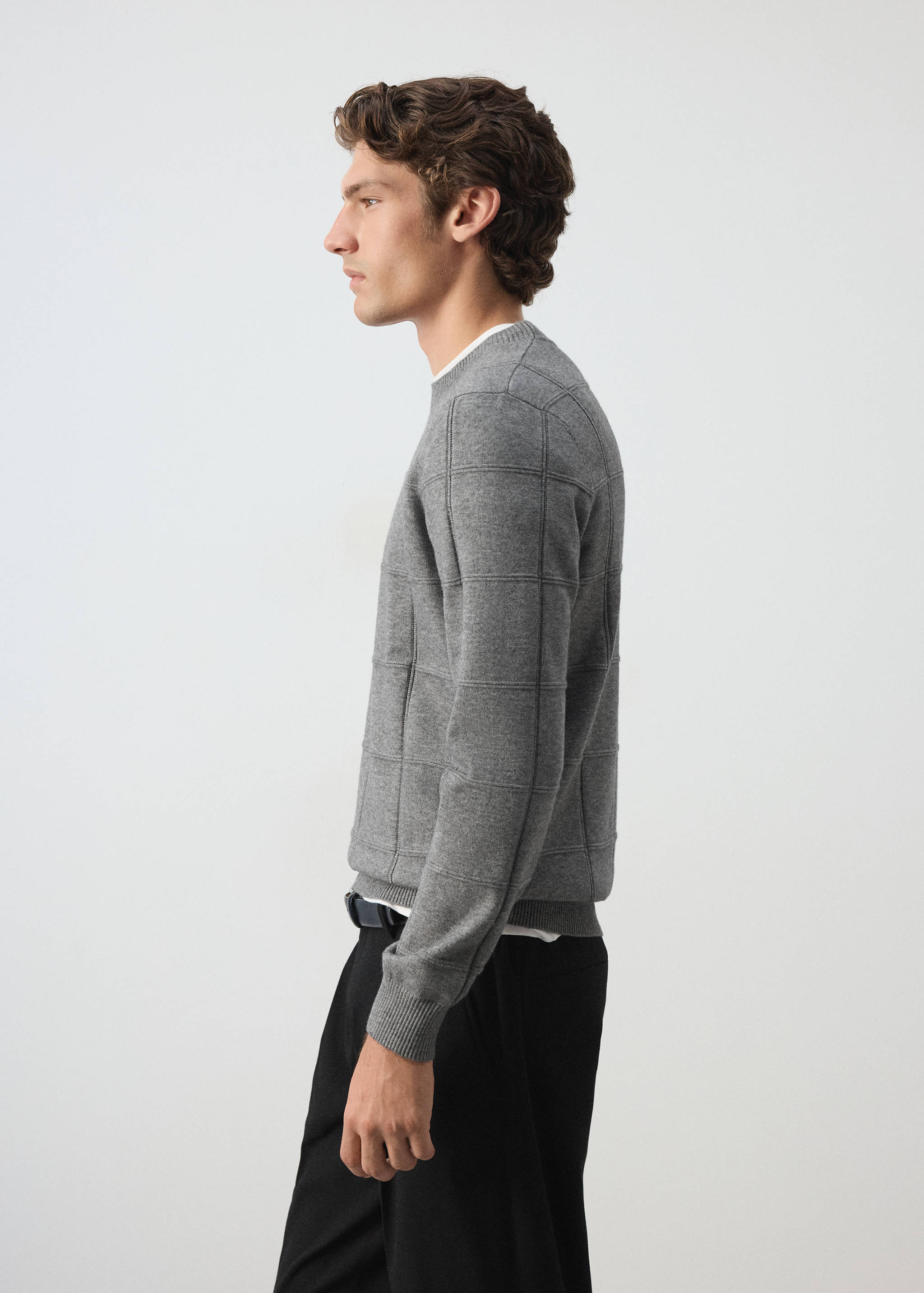 Grey crew neck knitted jersey with a checked pattern, worn by a male model.