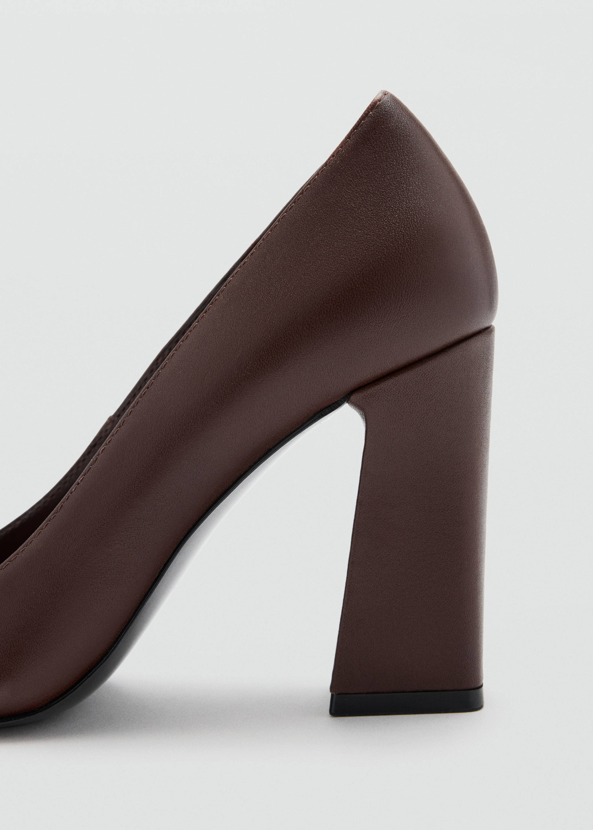 Close-up of a dark brown heeled shoe with a flared block heel.
