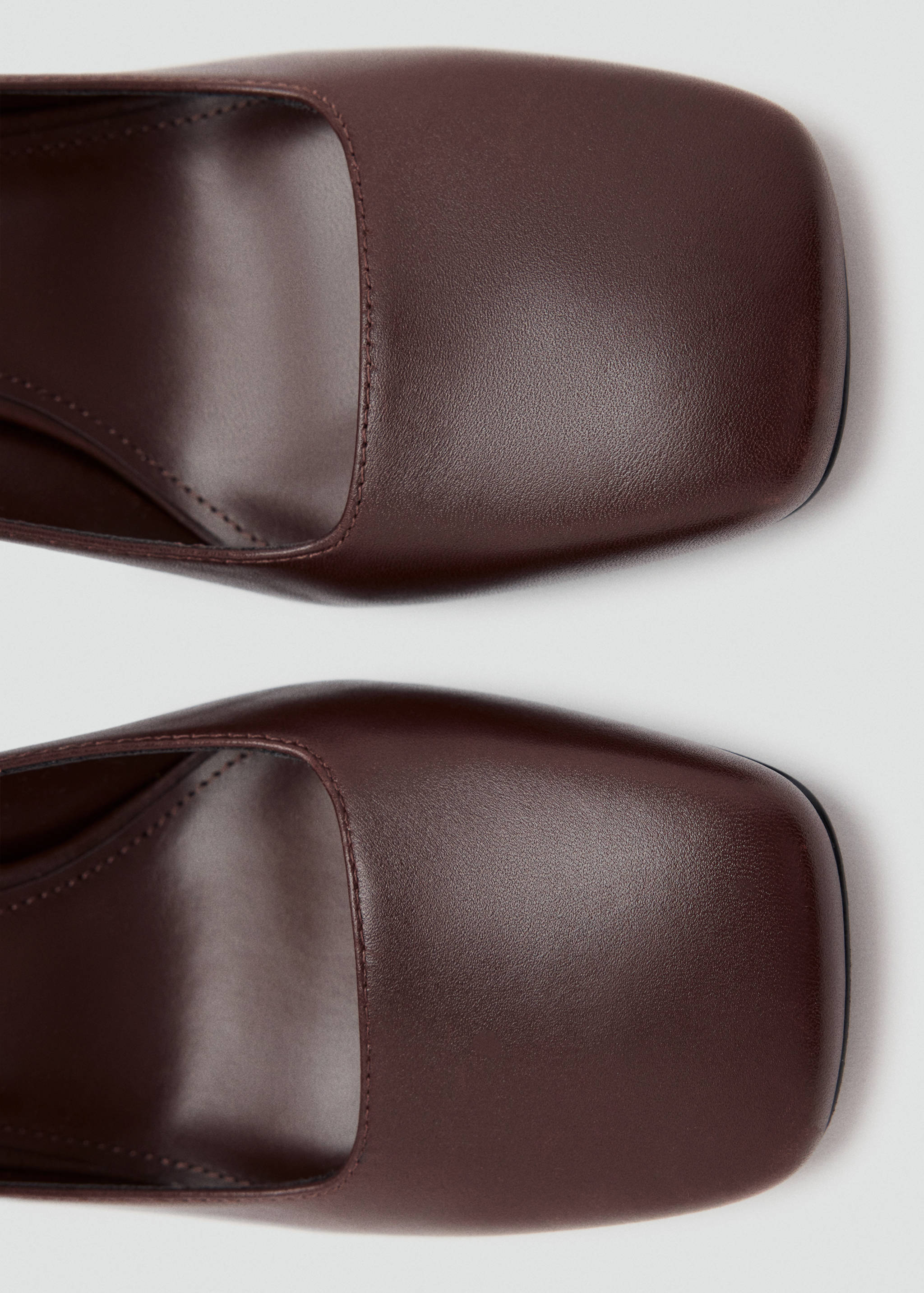 Close-up detail of dark brown square-toe shoes.