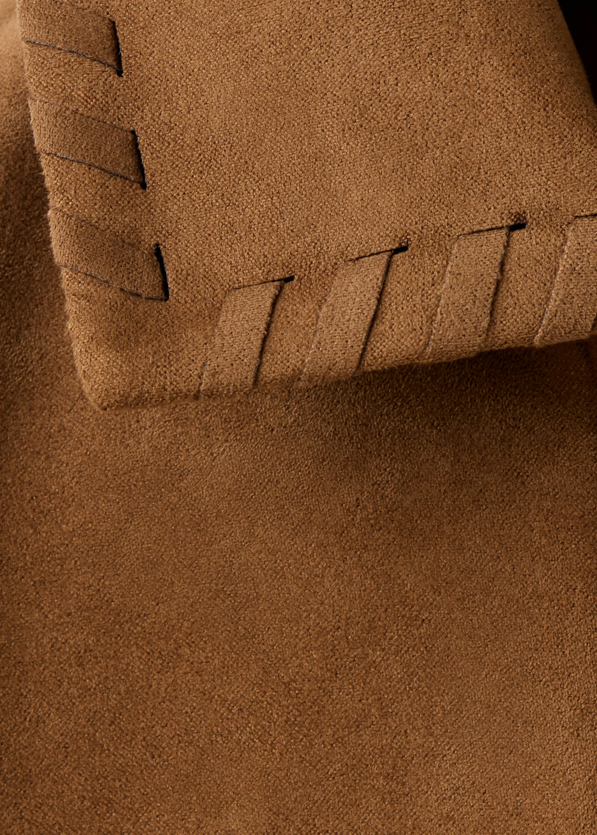 Brown jacket detail showing soft suede texture and whipstitch edge trim.