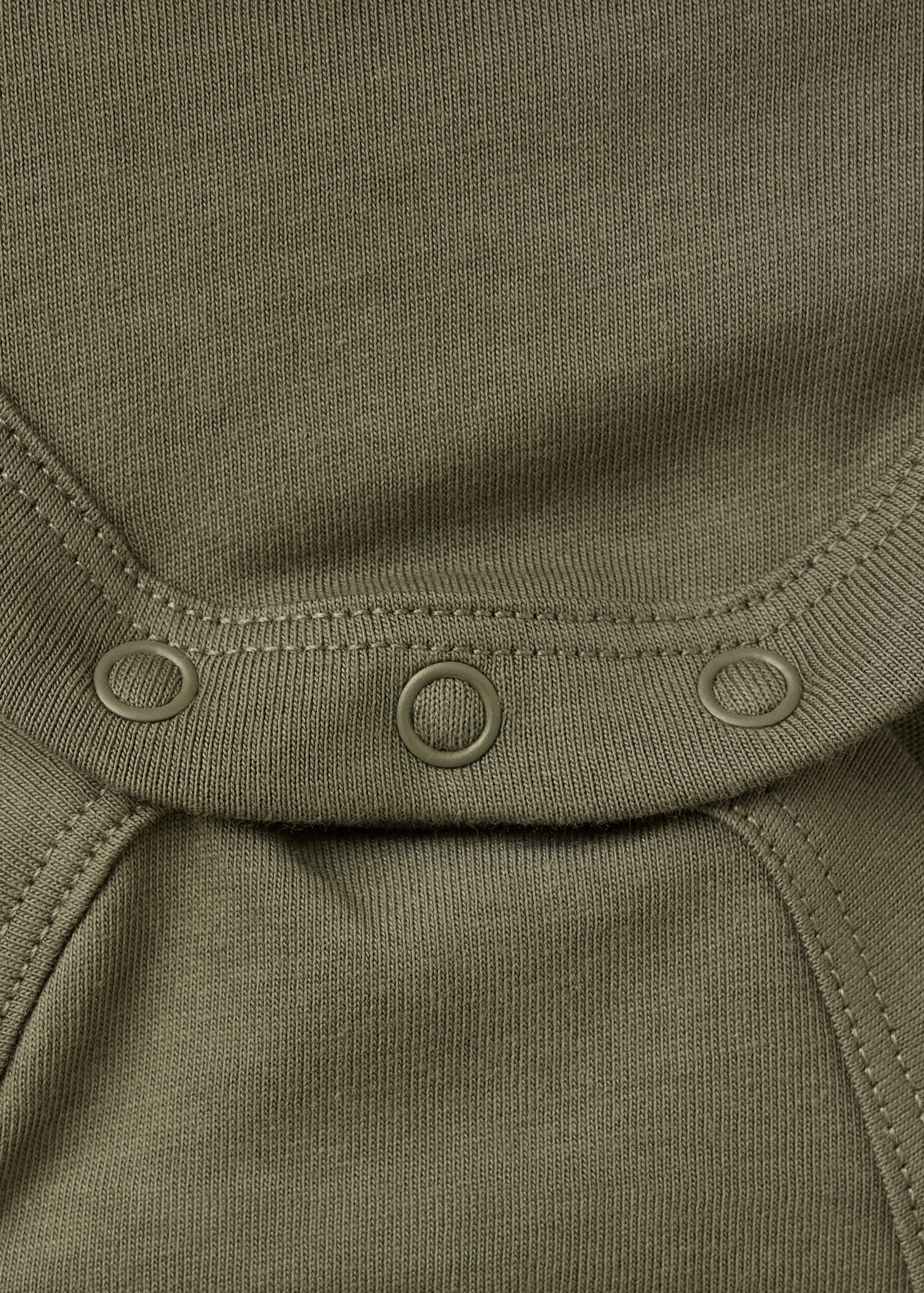 Close-up of an olive green baby body showing the fabric texture and snap buttons.