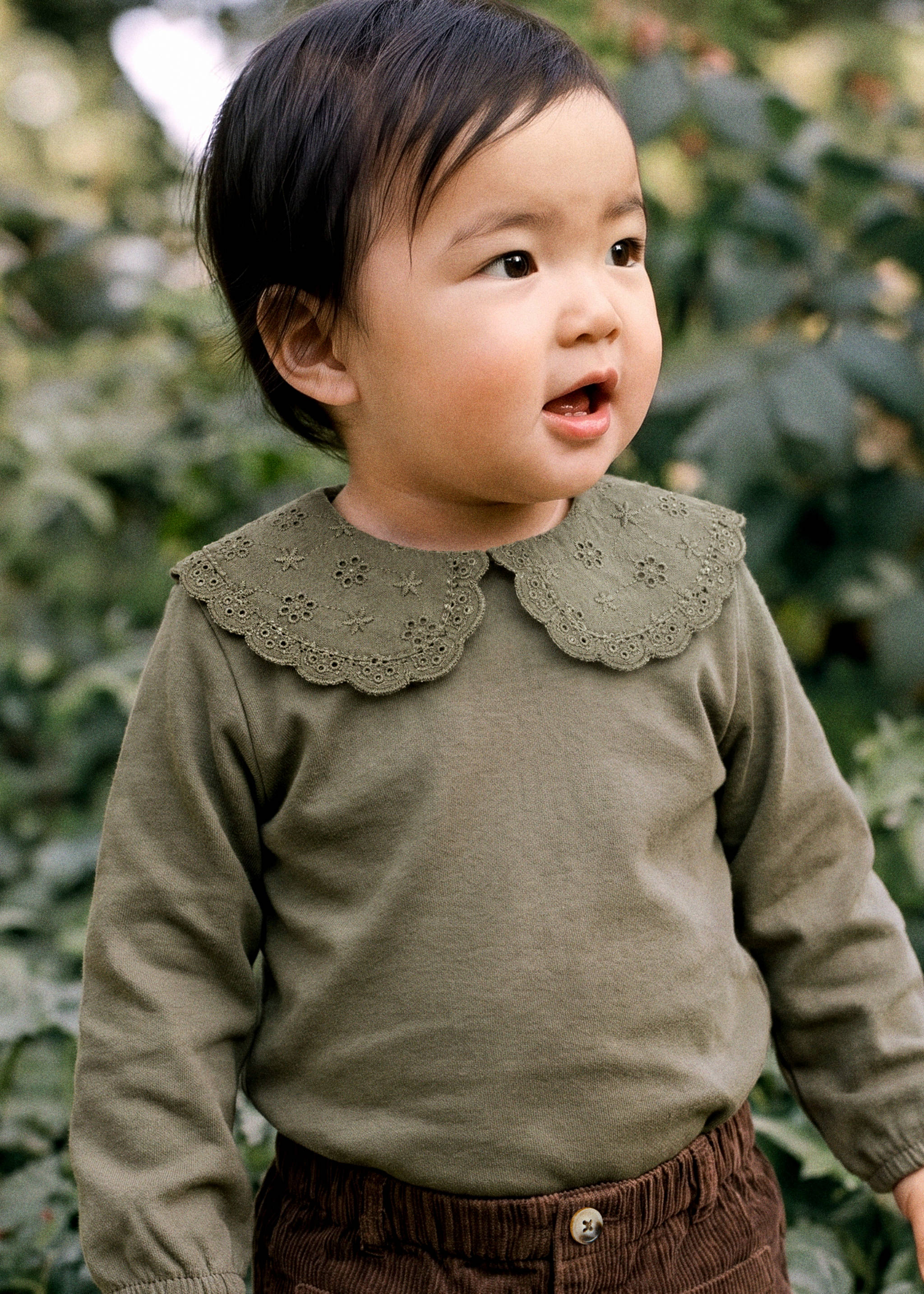 Olive green baby body with an embroidered eyelet scalloped collar and long sleeves