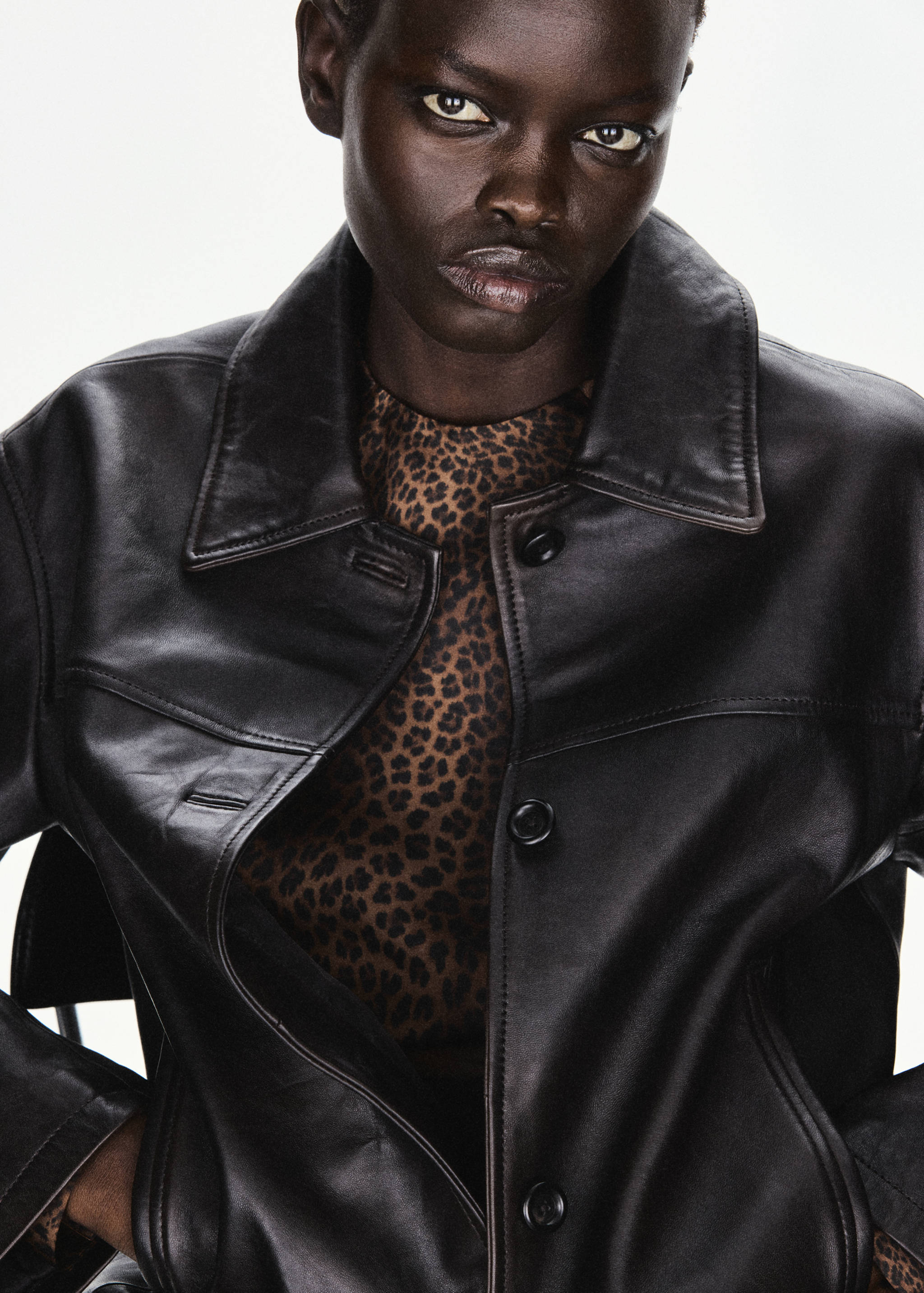 Leopard-print blouse worn under a dark leather jacket.