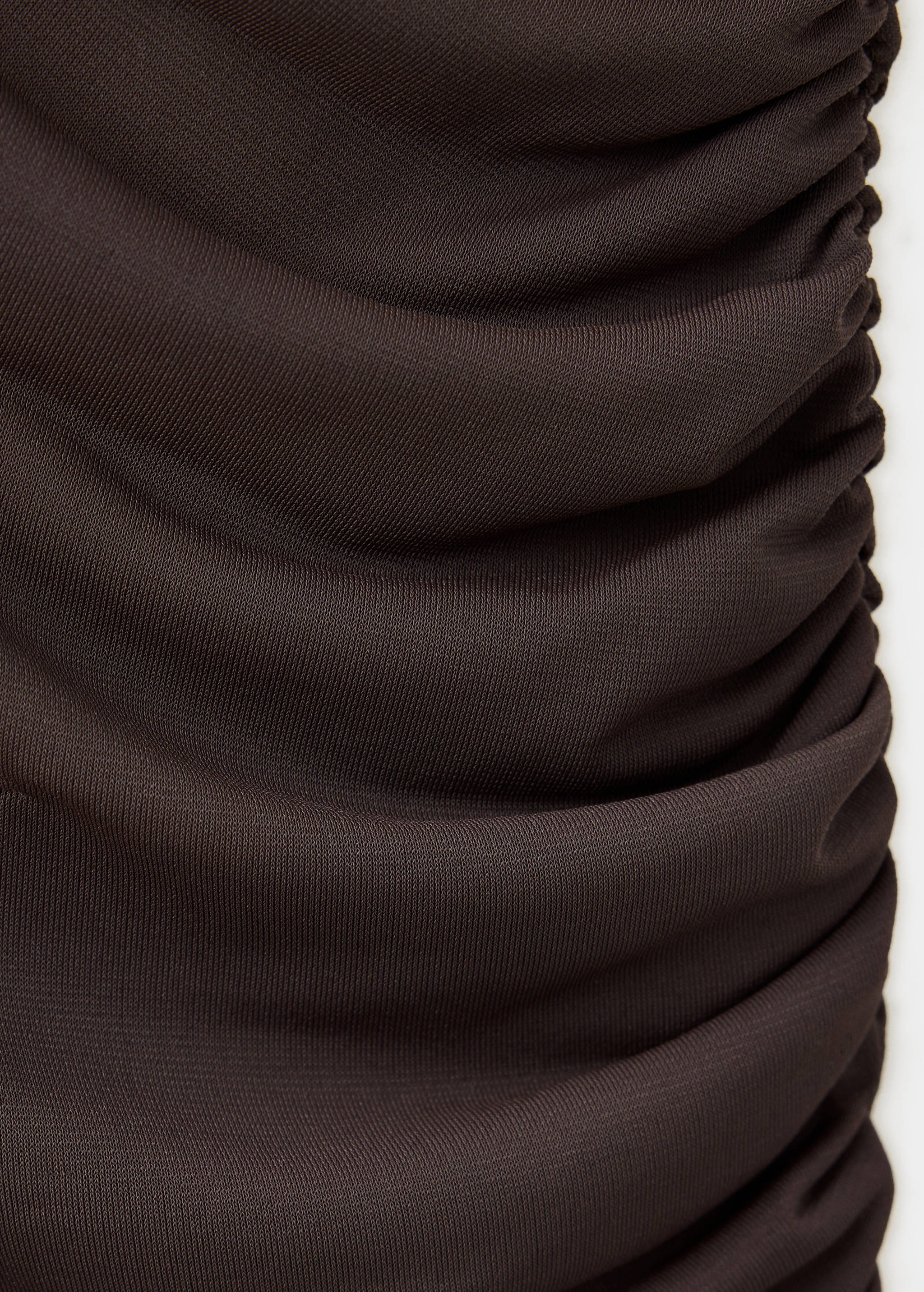 Close-up of the dark brown ruched fabric detail of a dress.