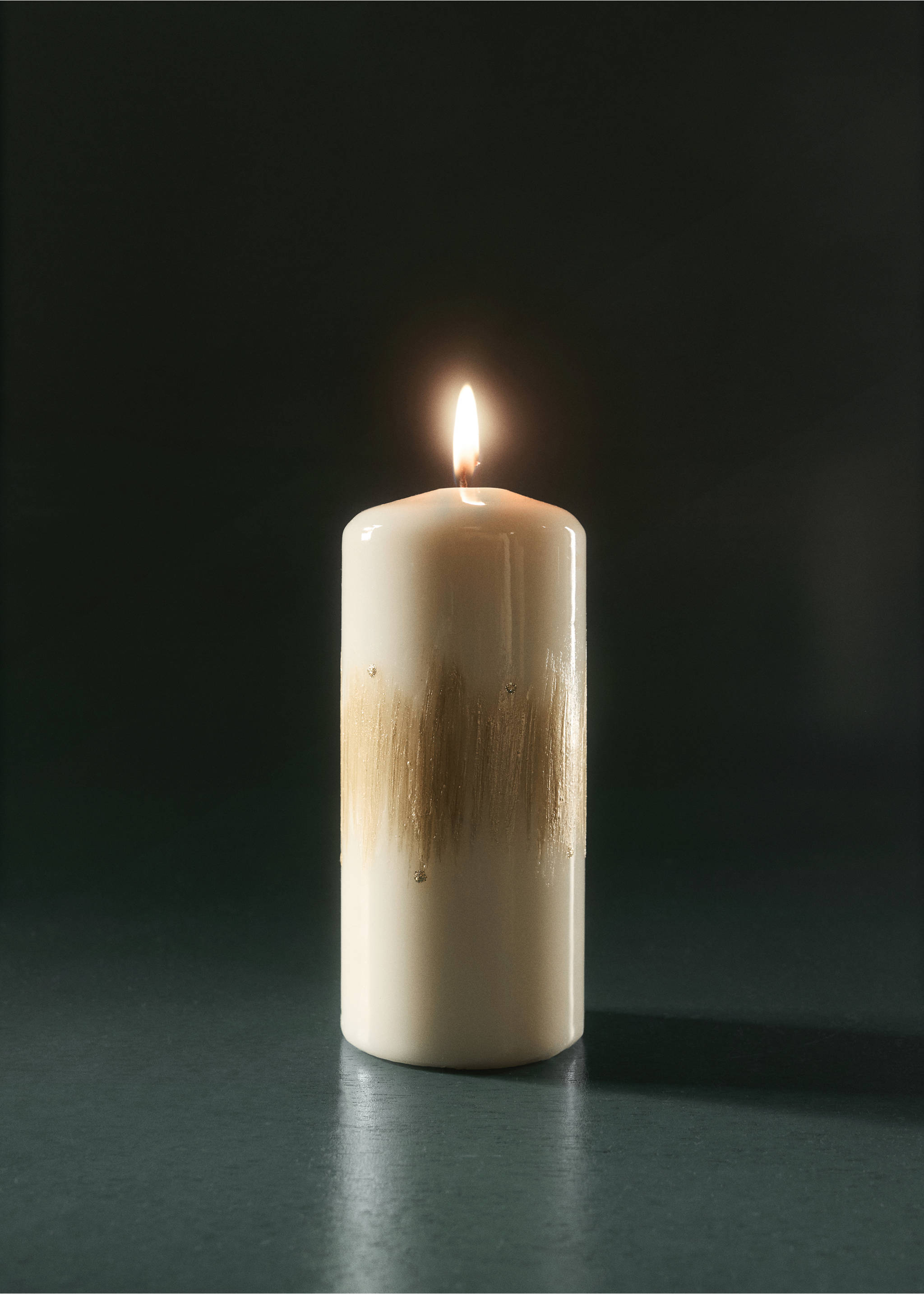 Lit cream pillar candle with gold brushstroke detailing., Gold. Ref: 37027942-00.