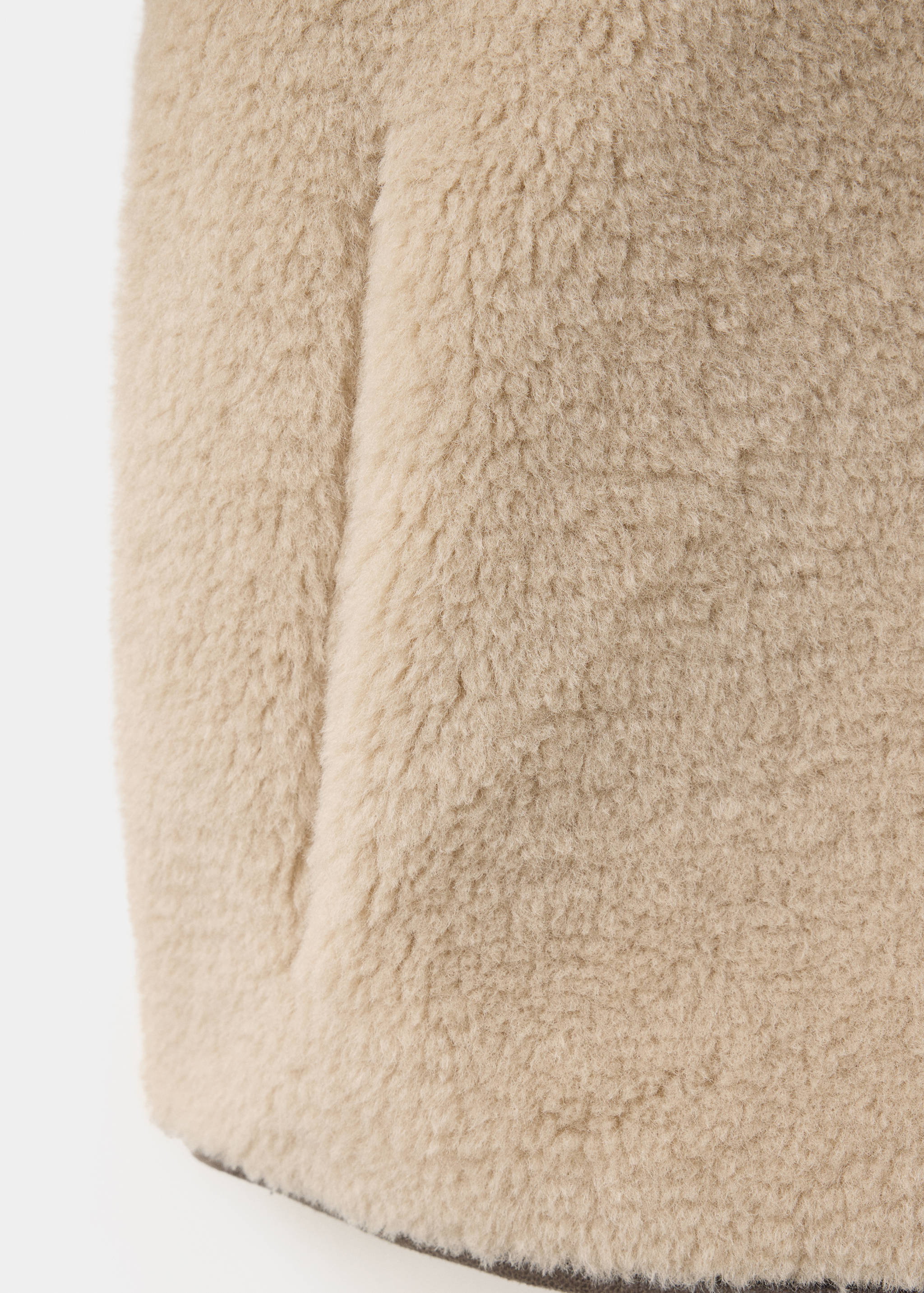 Primer plano del tejido beige de abrigo de borreguillo sintético.
