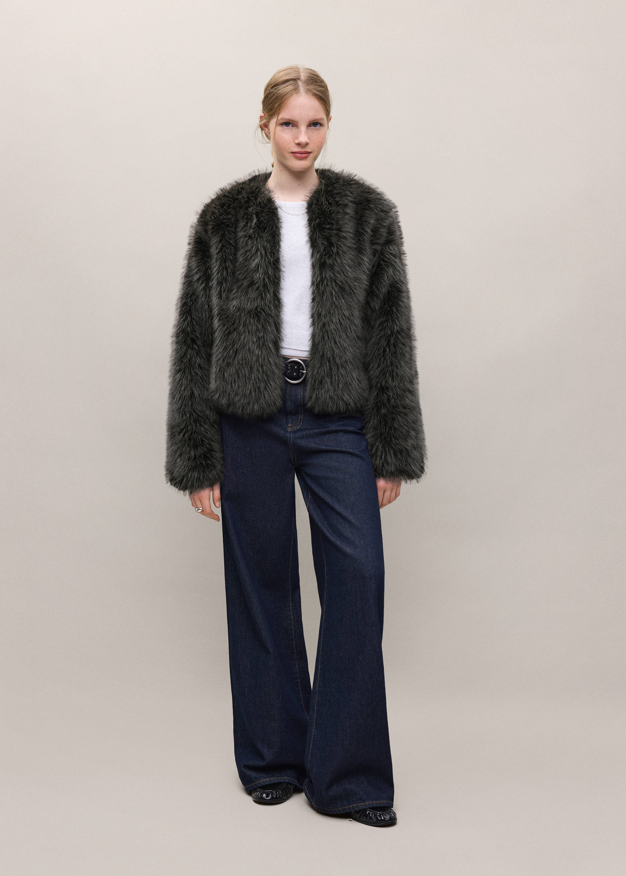 Dark grey collarless faux-fur coat worn with a white top and dark blue wide-leg trousers.