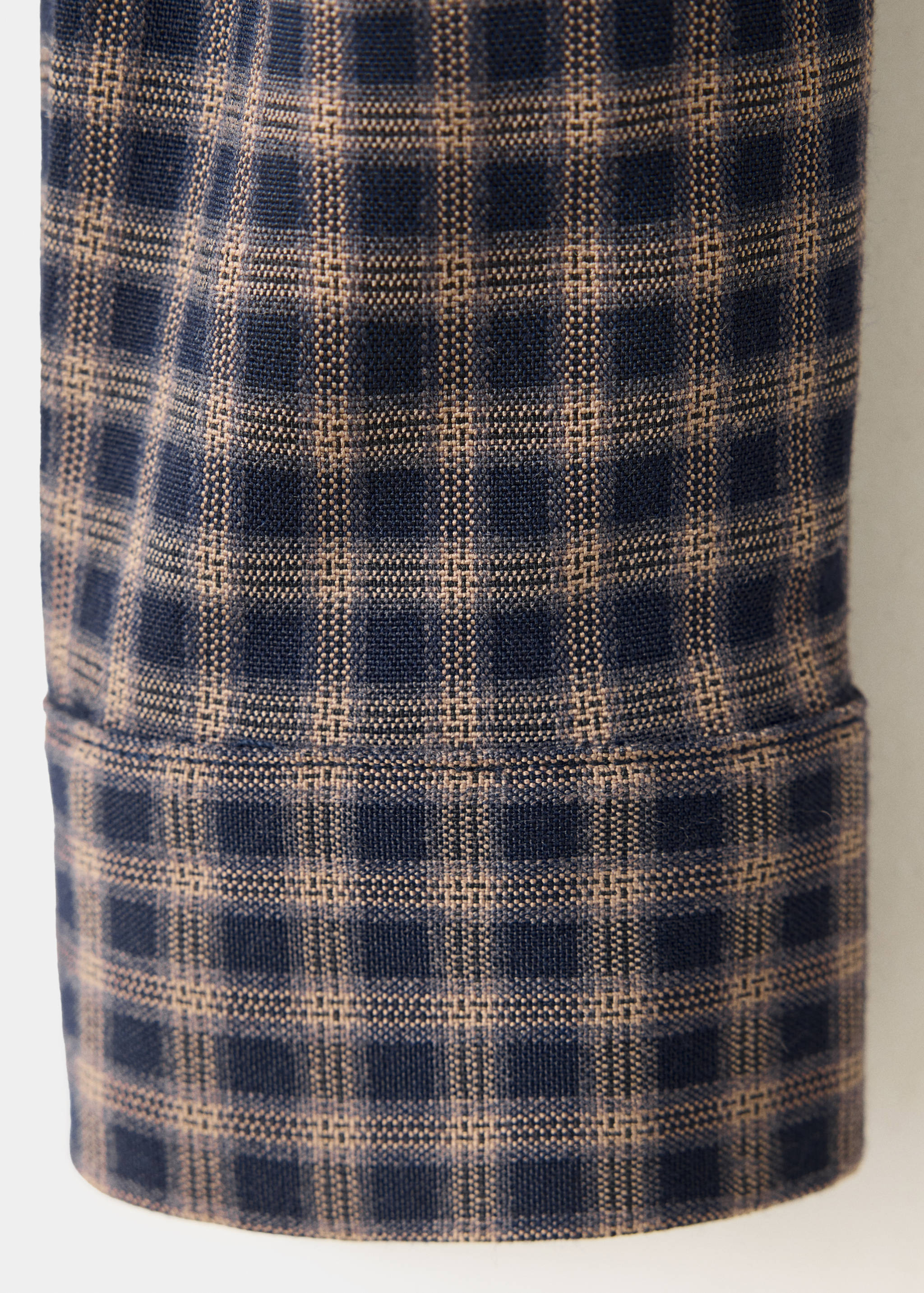 Close-up of the navy blue and brown check fabric and cuff detail on a children's shirt.