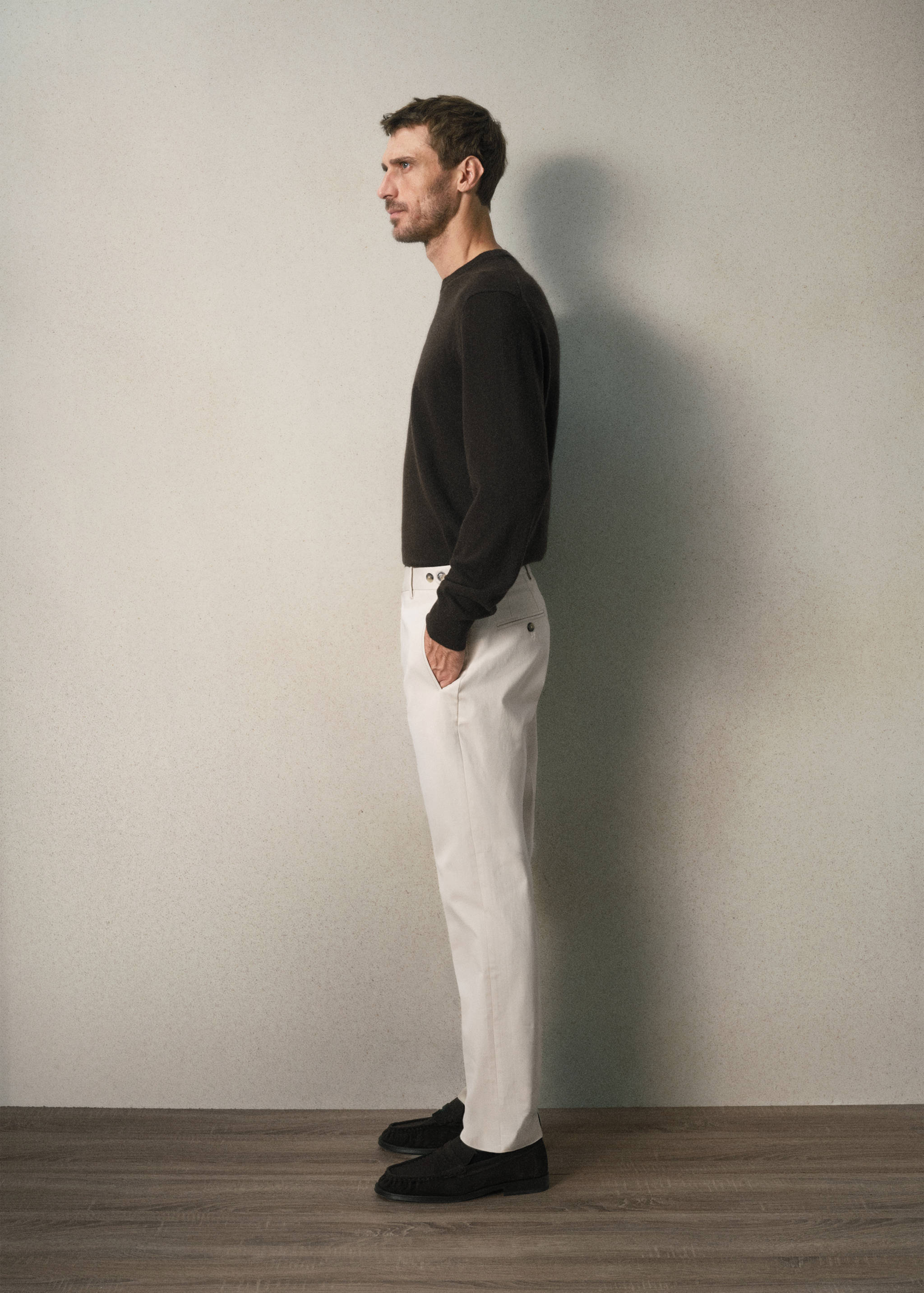 Off-white slim-fit trousers worn with a dark sweater and loafers.